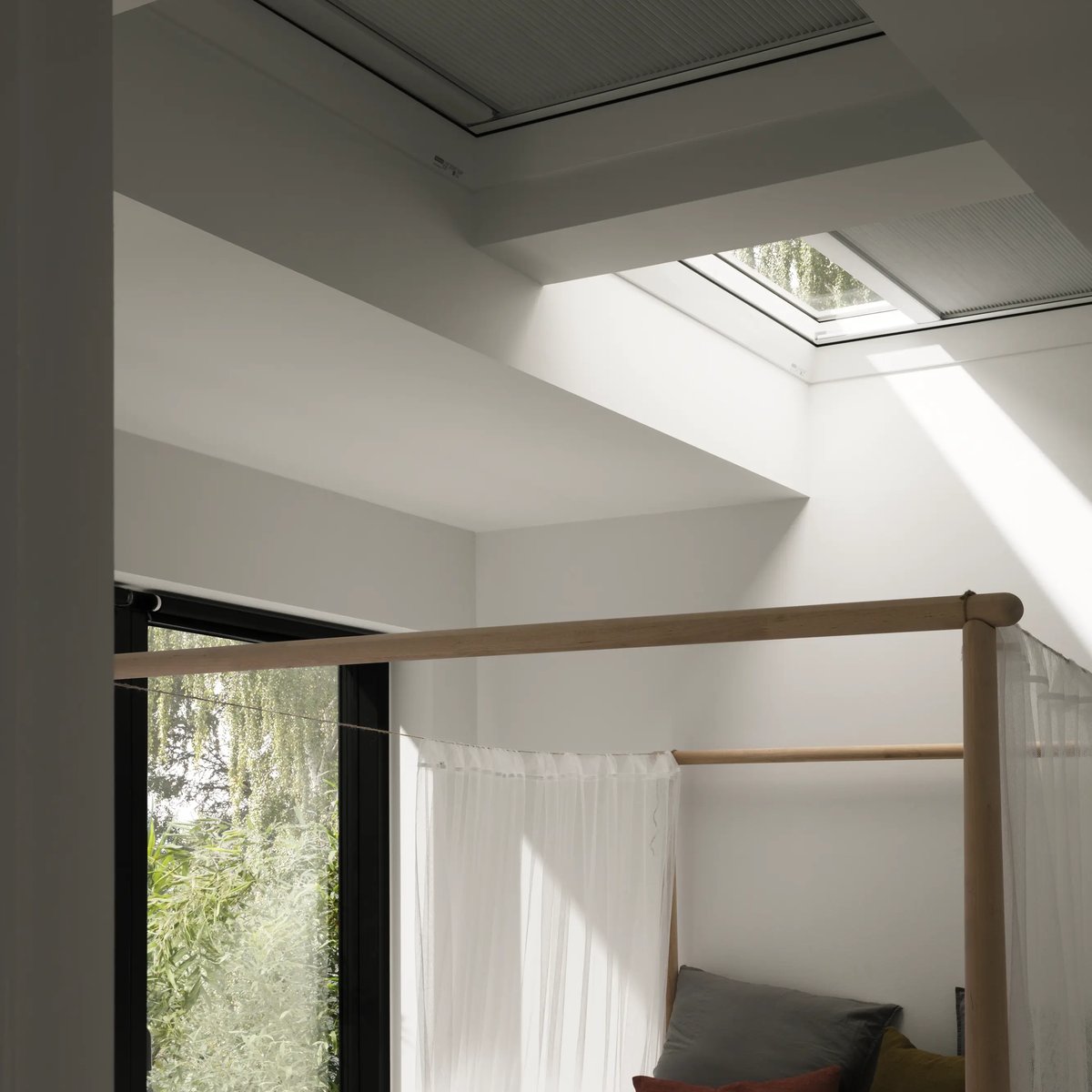 Bedroom with VELUX roof window, natural light and greenery view.