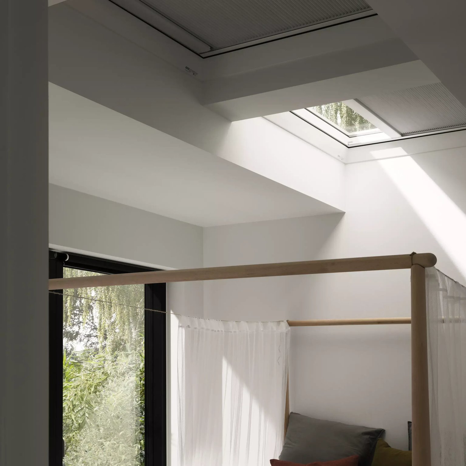 Bedroom with VELUX roof window, natural light and greenery view.
