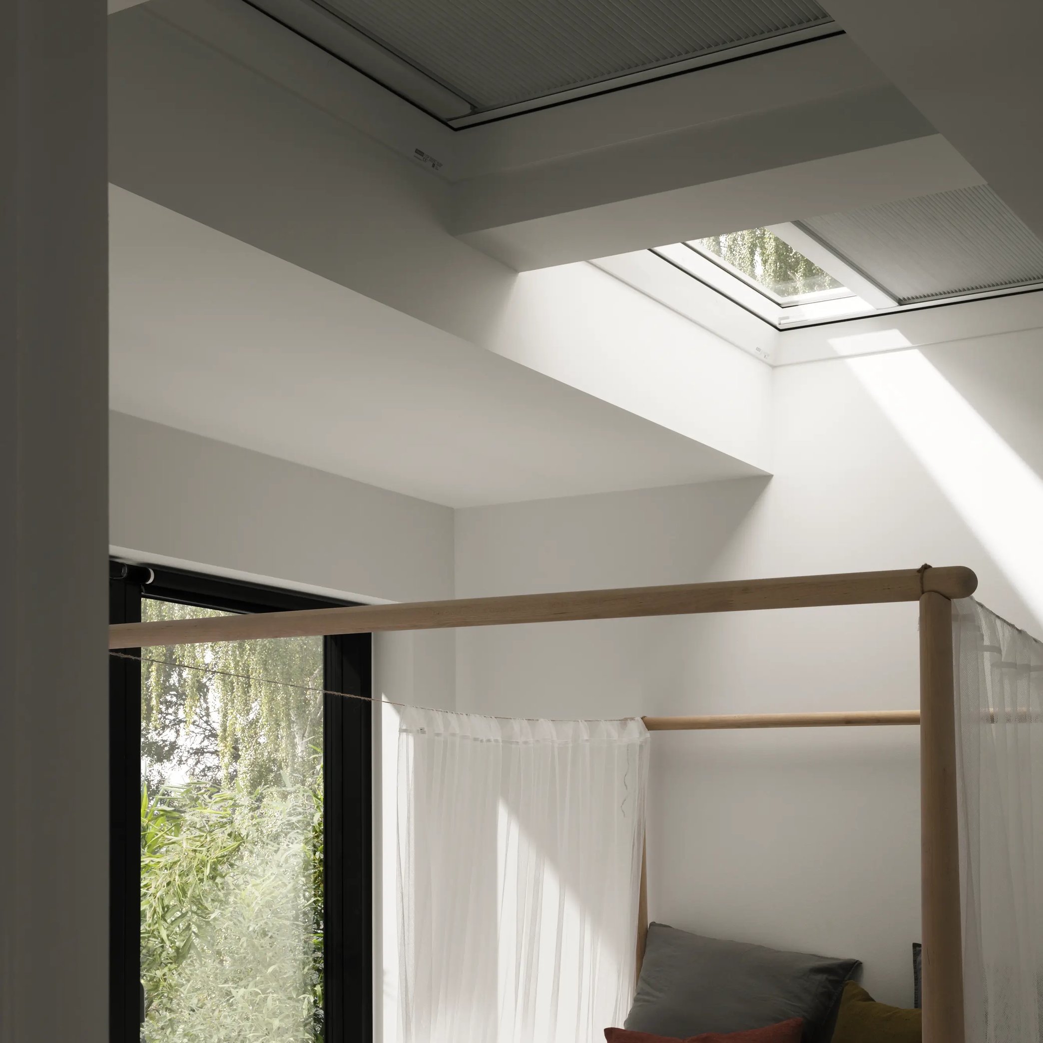 Bedroom with VELUX roof window, natural light and greenery view.