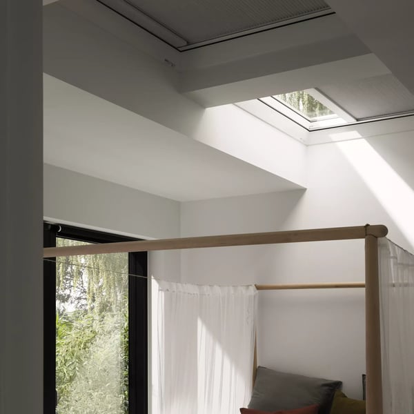 Bedroom with VELUX roof window, natural light and greenery view.