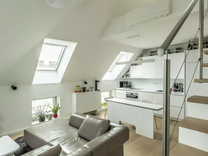 Zeitgemäßer Dachboden-Wohnbereich mit Ledersofa, Küche und VELUX Dachflächenfenster.