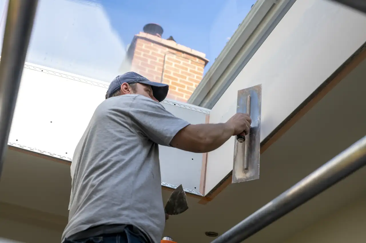 Worker installing drywall near VELUX roof window, natural light entering