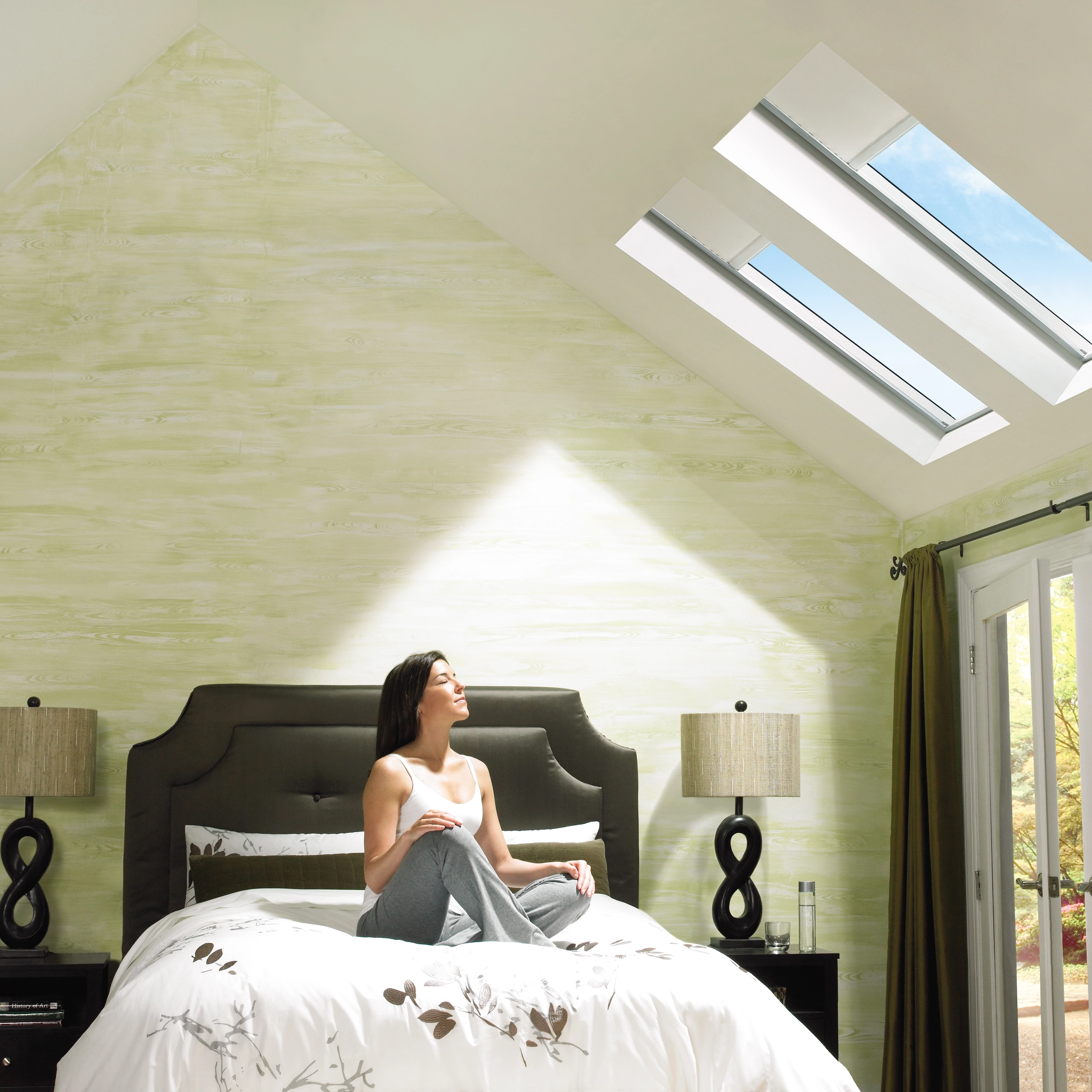 Bedroom with sloped ceiling and VELUX roof windows, natural light entering.