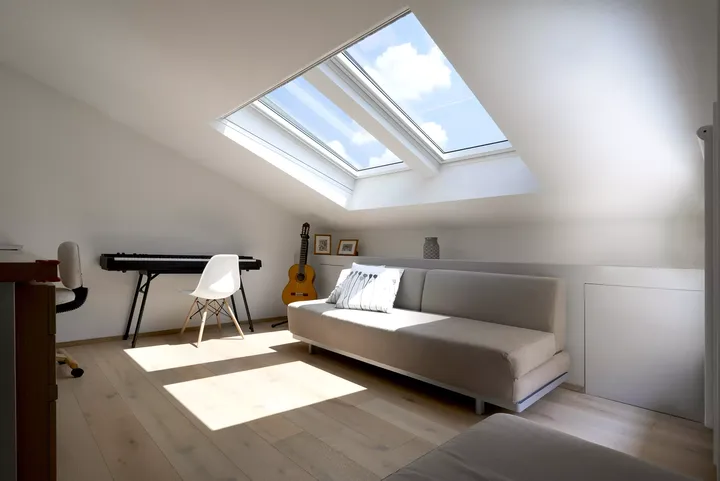Dachboden-Musikzimmer mit VELUX Dachflächenfenster, Sofa, Klavier und Gitarre.