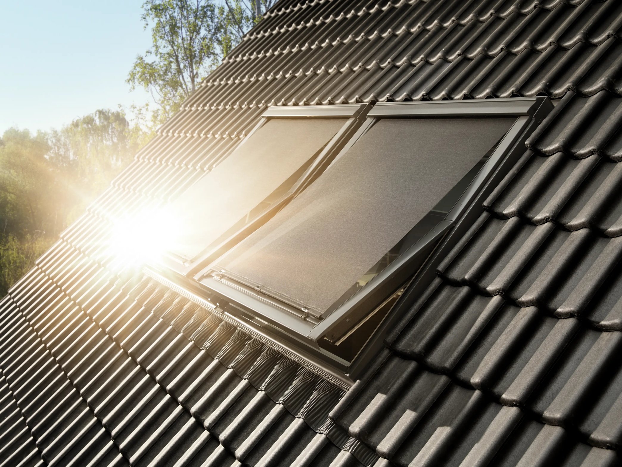Sunlit roof with VELUX roof windows and dark ceramic tiles.