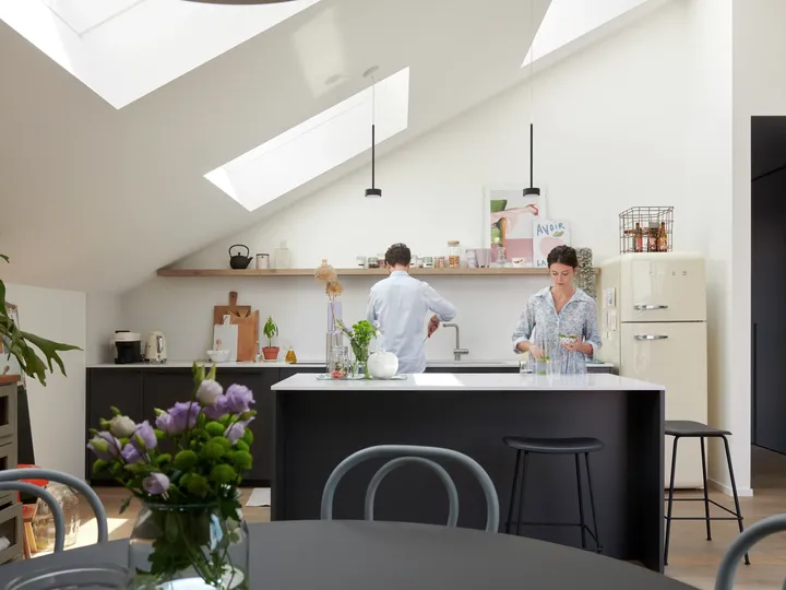 Helle moderne Küche mit zentraler Insel, schwarzen Arbeitsplatten und VELUX Dachflächenfenster.