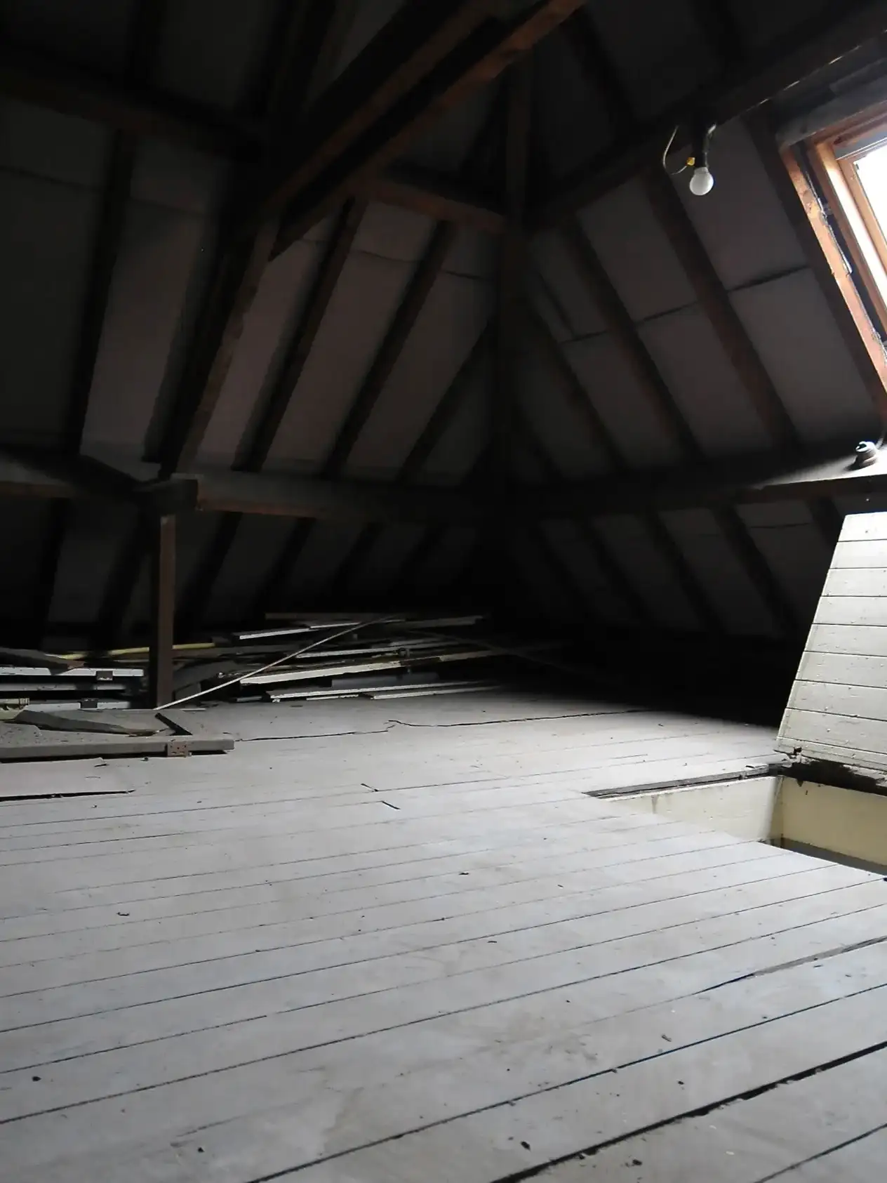 combles sombres avec rais de lumière venant d’une fenêtre de toit