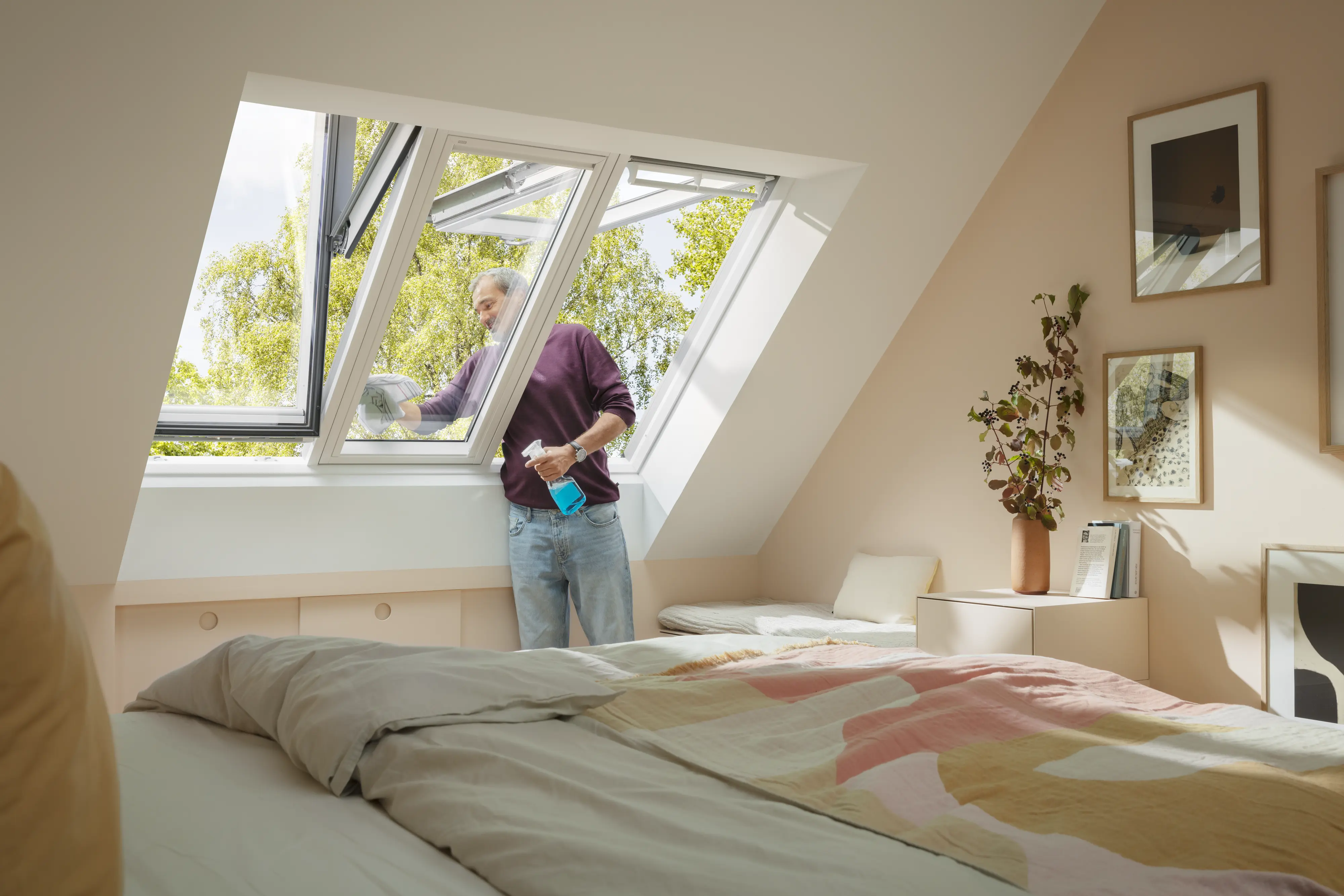 Attic bedroom with sloped ceiling and open VELUX roof window, natural light entering.