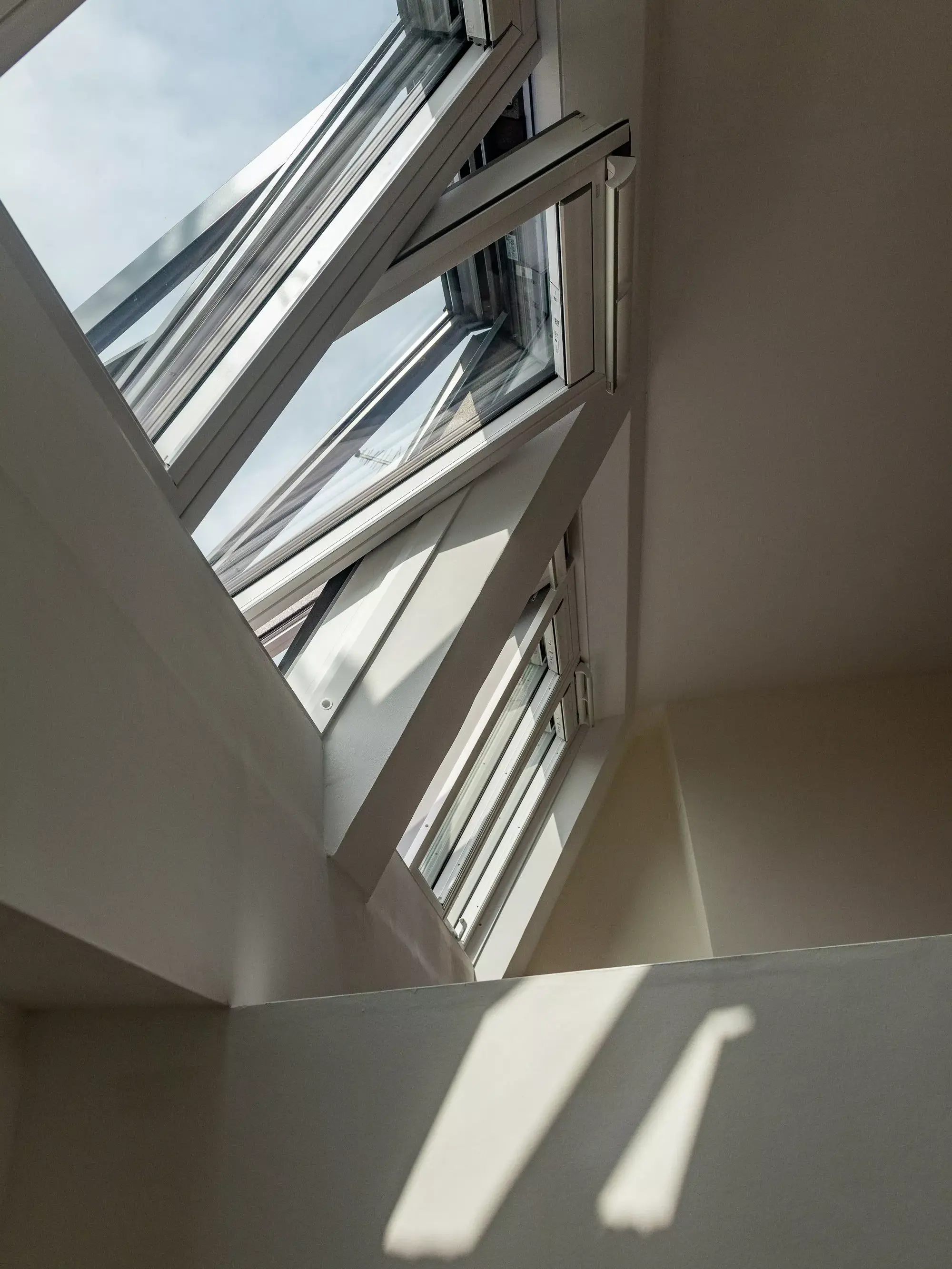Lumière du soleil à travers une fenêtre de toit VELUX ouverte dans une chambre de comble sereine.