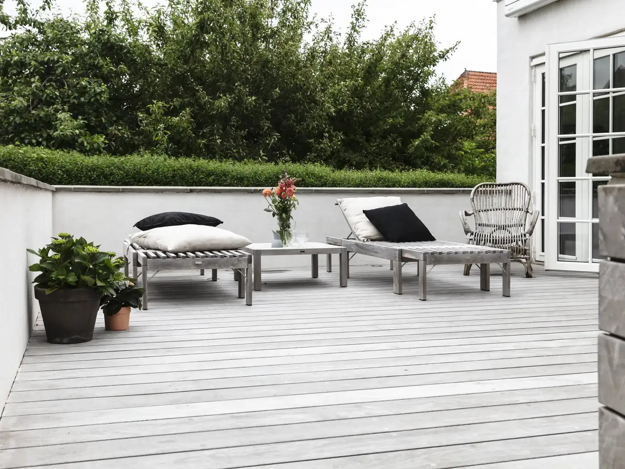 terrasse sur toit plat aménagée avec sol en lames claires, assises, plantes et accès depuis la maison