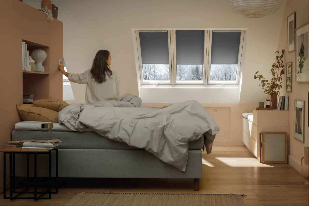 Uporabnik nadzoruje strešna okna VELUX prek mobilne aplikacije.