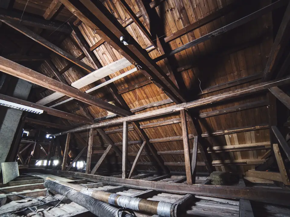 Attic room with exposed wooden rafters and sloped ceiling.