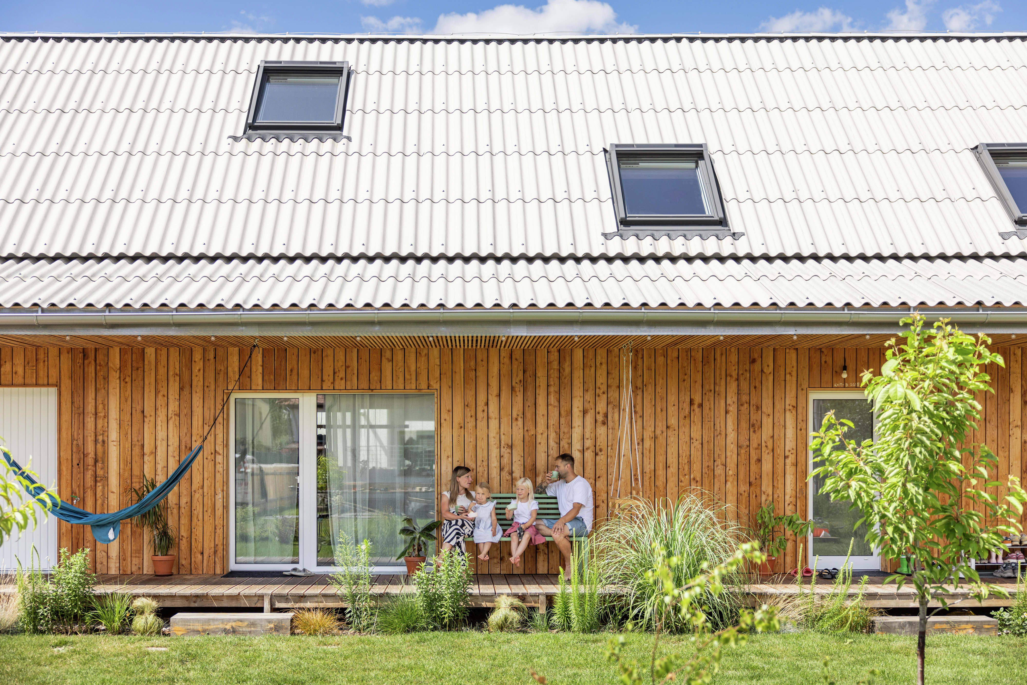 Wooden house with metal roof and VELUX roof windows, garden view.