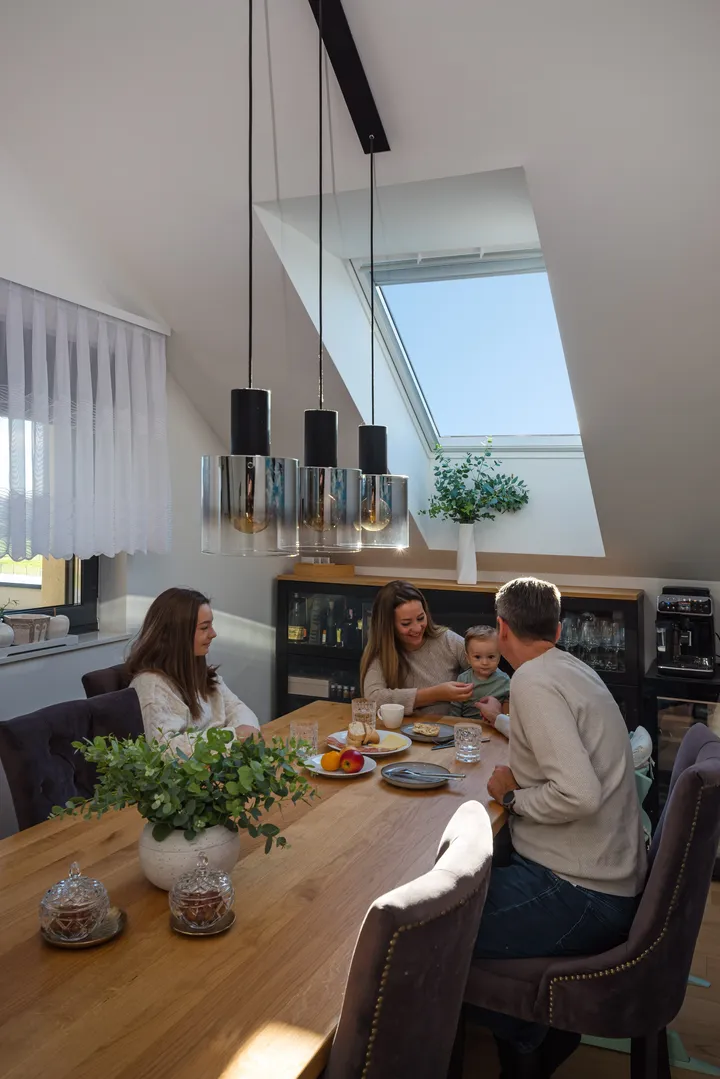 Трапезария със скосен таван и покривен прозорец VELUX, с проникване на естествена светлина.