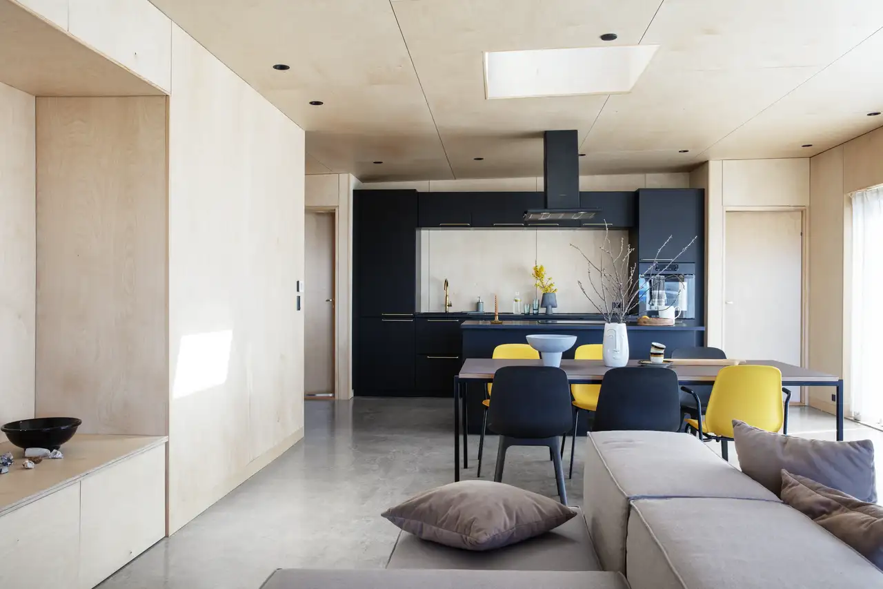 Cuisine-séjour ordonné avec mobilier épuré et chaises jaunes apportant une touche lumineuse et joyeuse