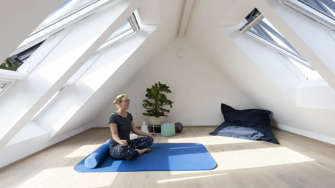 Frau macht Yoga-Übung im Spitzboden bei geöffneten Dachfenstern | VELUX Magazin