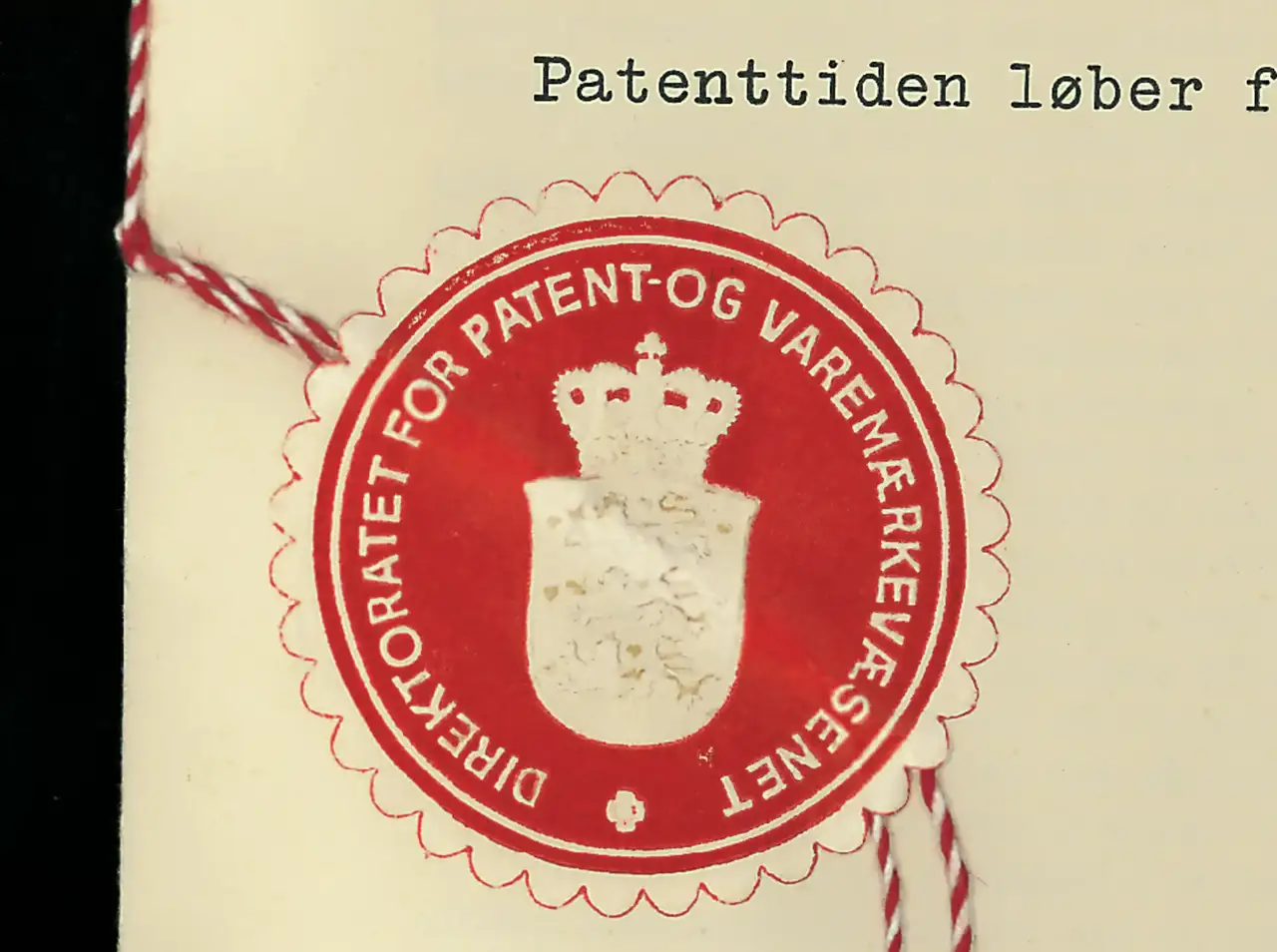 Nahaufnahme eines roten Vintage-Patentsiegels mit einer Kronenemblem und rot-weißer Schnur.