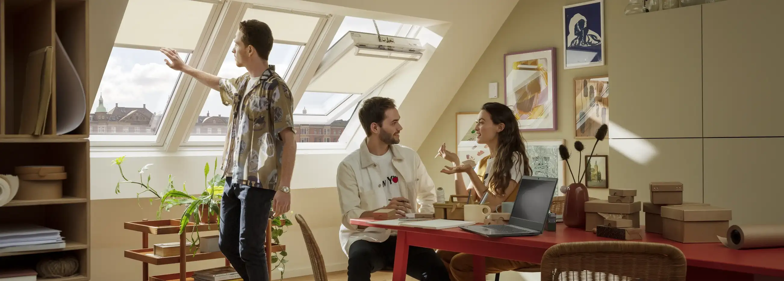 Attic workspace with sloped ceiling and large roof windows, natural light entering.