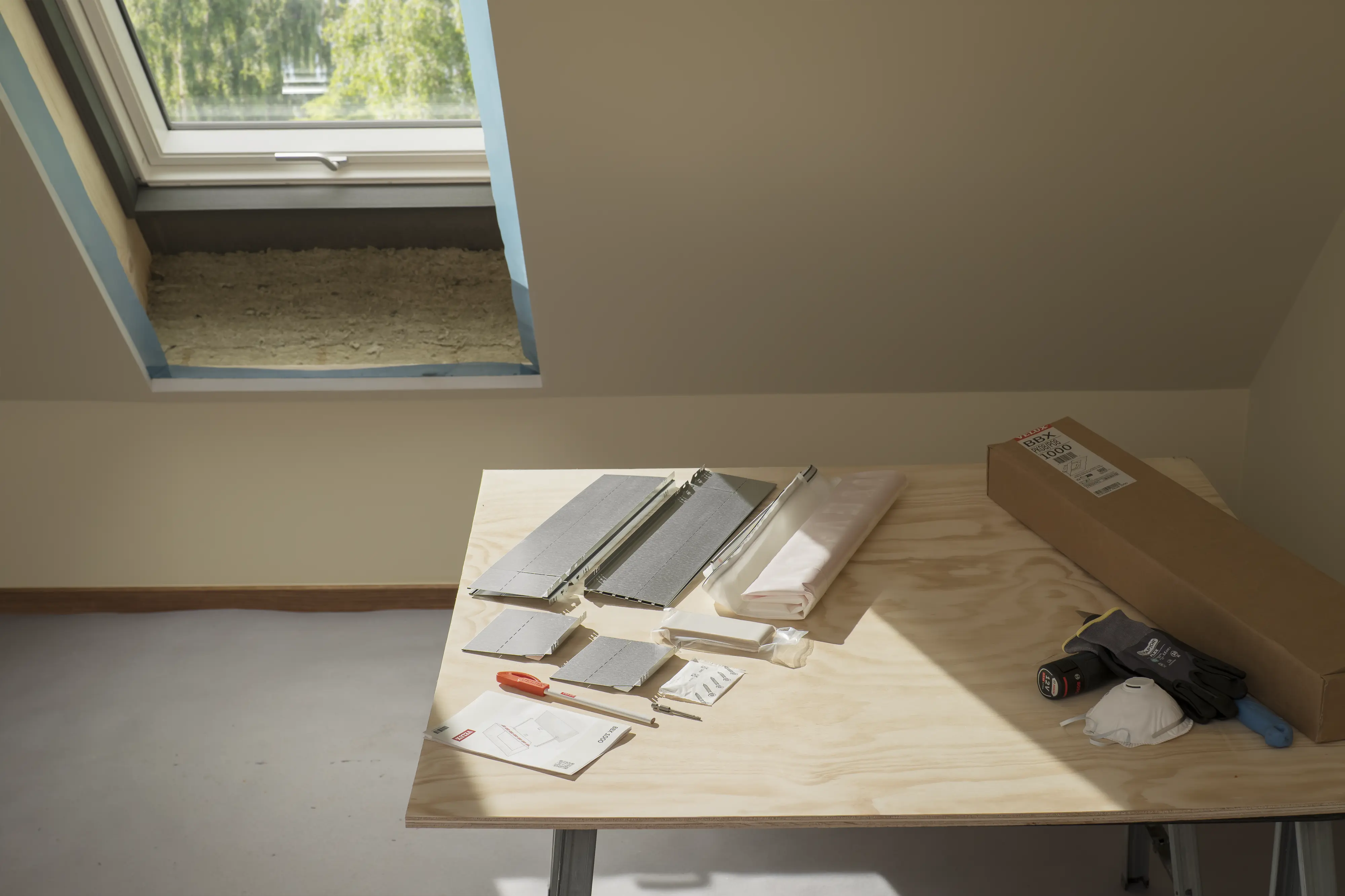 Attic room with VELUX roof window, overview of sub-construction materials on table.