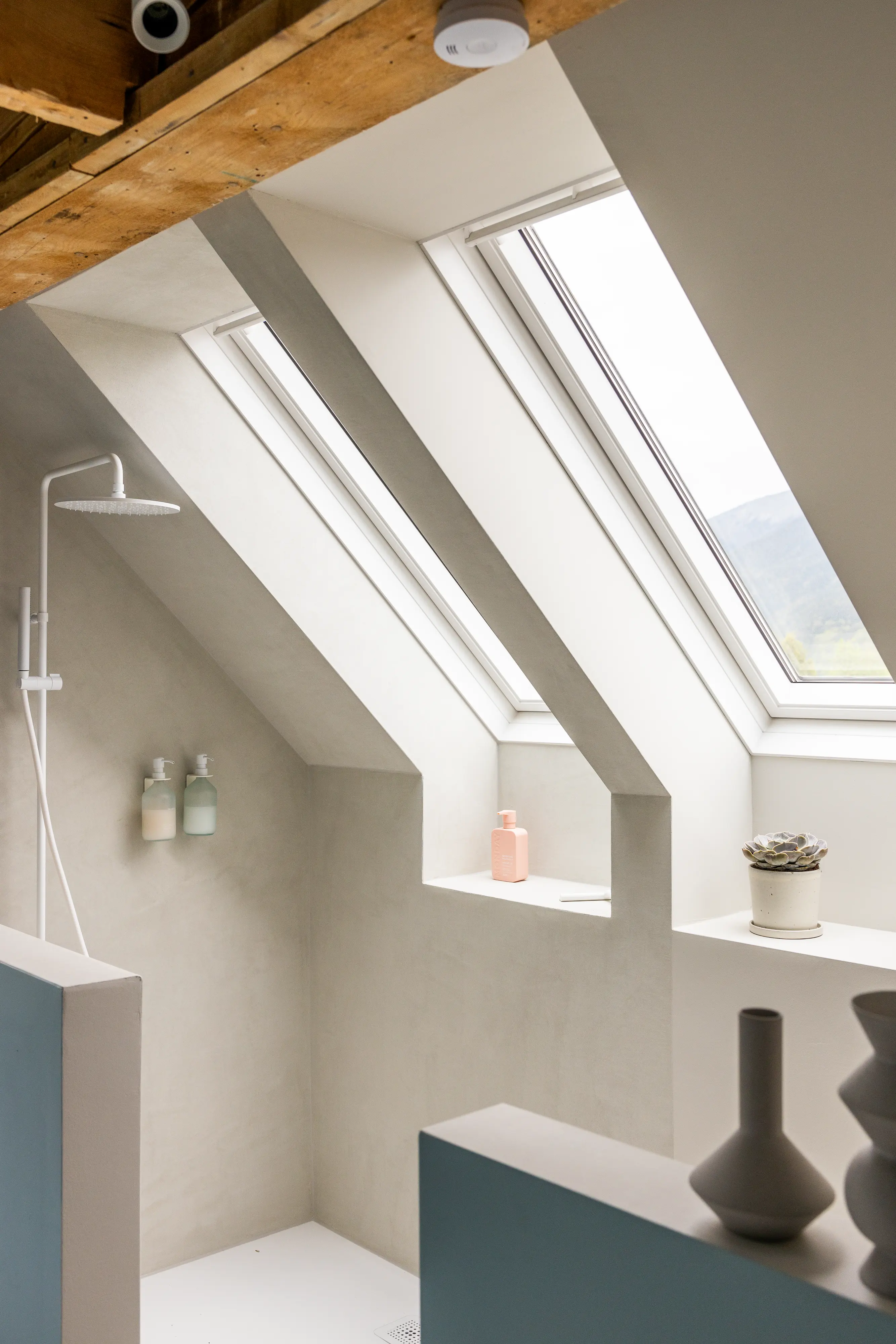 Palėpės vonios kambarys su nuožulniomis lubomis ir VELUX stogo langais, modernus dizainas.