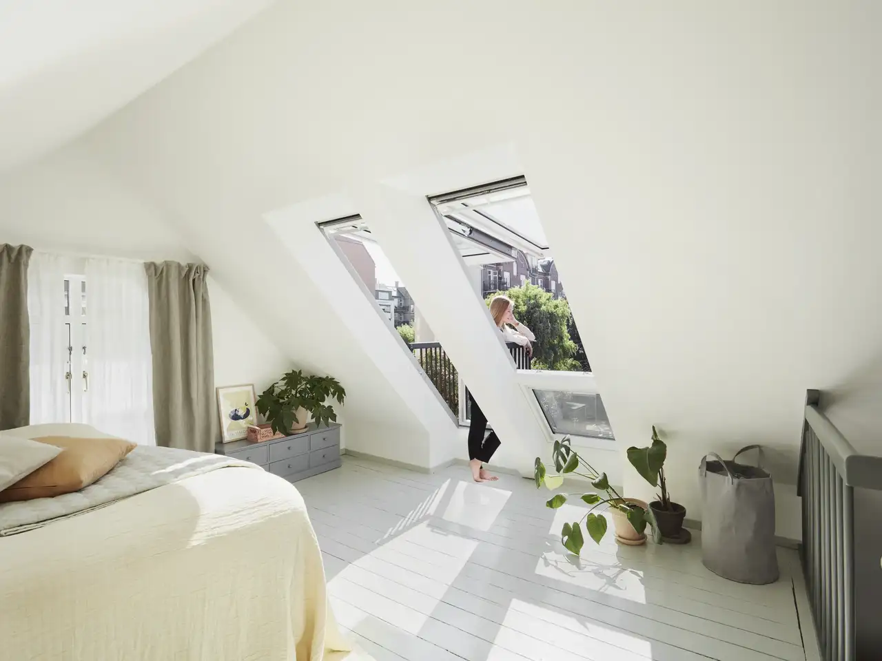 Giovane donna che si gode il sole sul balcone sul tetto durante la sua vacanza in mansarda | Rivista VELUX