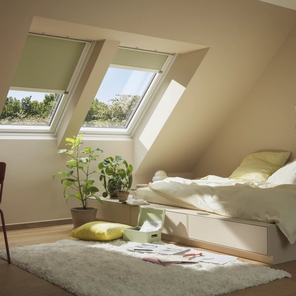 Attic kid's room with sloped ceiling and closed VELUX roof window with VELUX blinds, cozy decor.