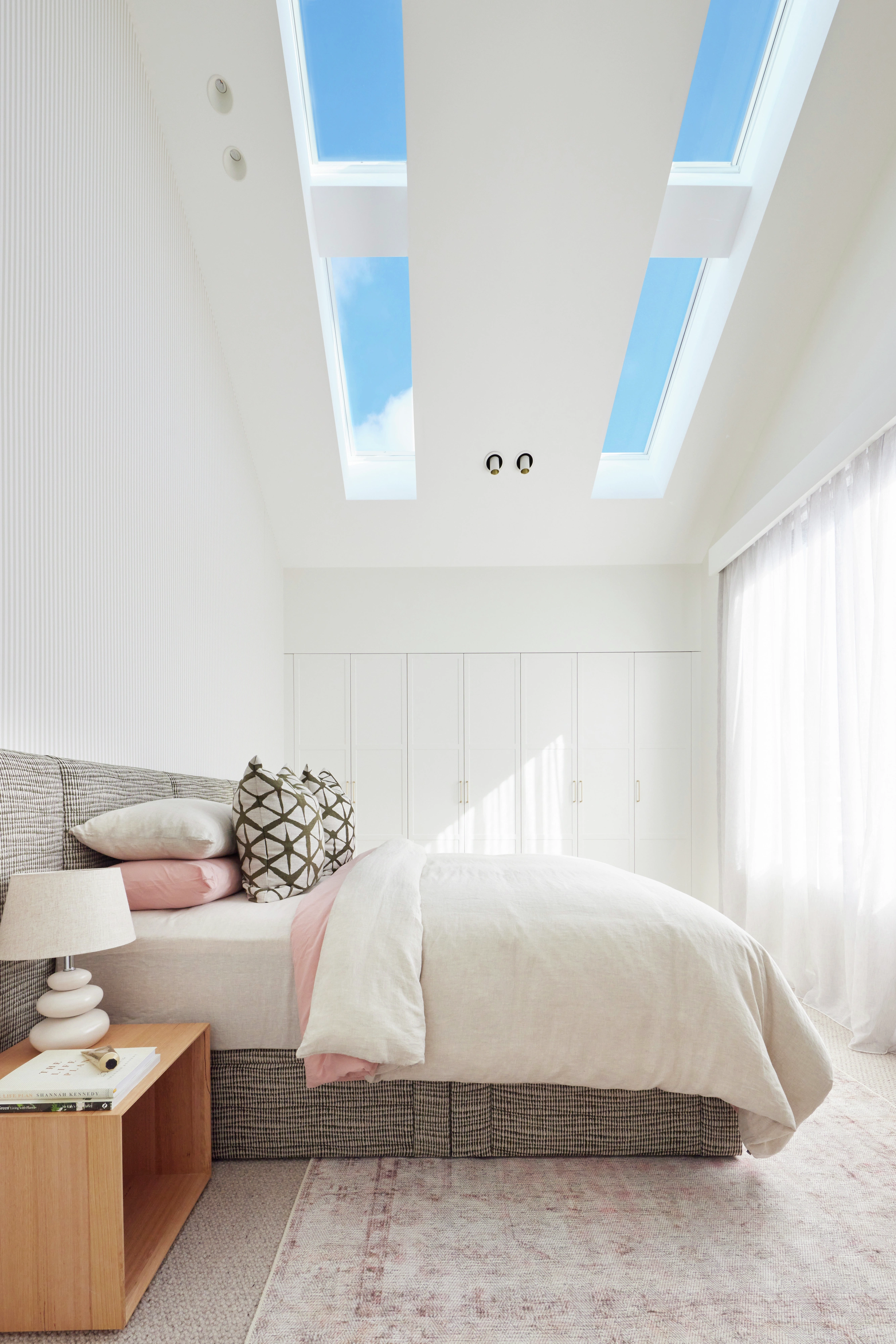 Bedroom with skylights and soft decor.