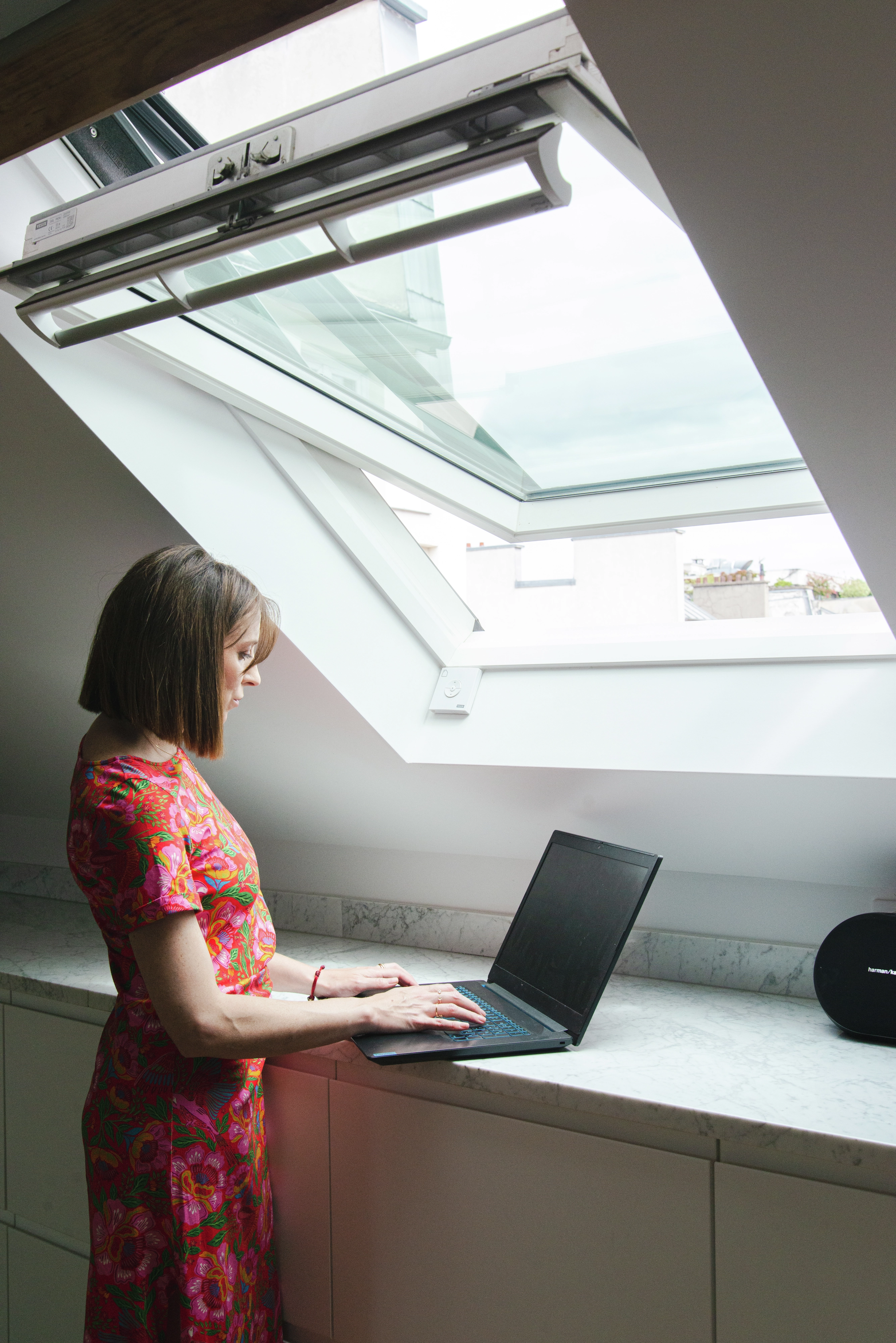 Bureau à domicile avec fenêtre de toit VELUX, bureau en marbre et ordinateur portable, sous un ciel transparent.