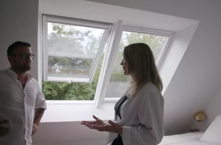 Couple standing in the bedroom next to 2 velux roof windows
