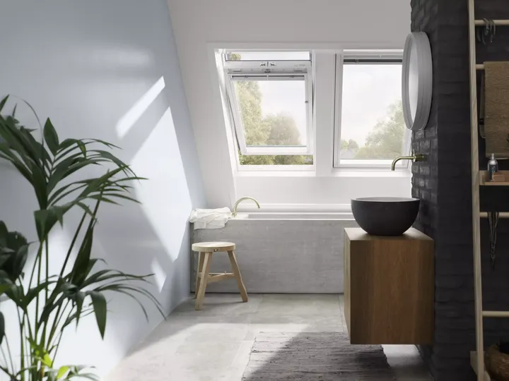 Modernes Badezimmer mit VELUX Dachflächenfenster, Steinwand und hölzernem Waschtisch.