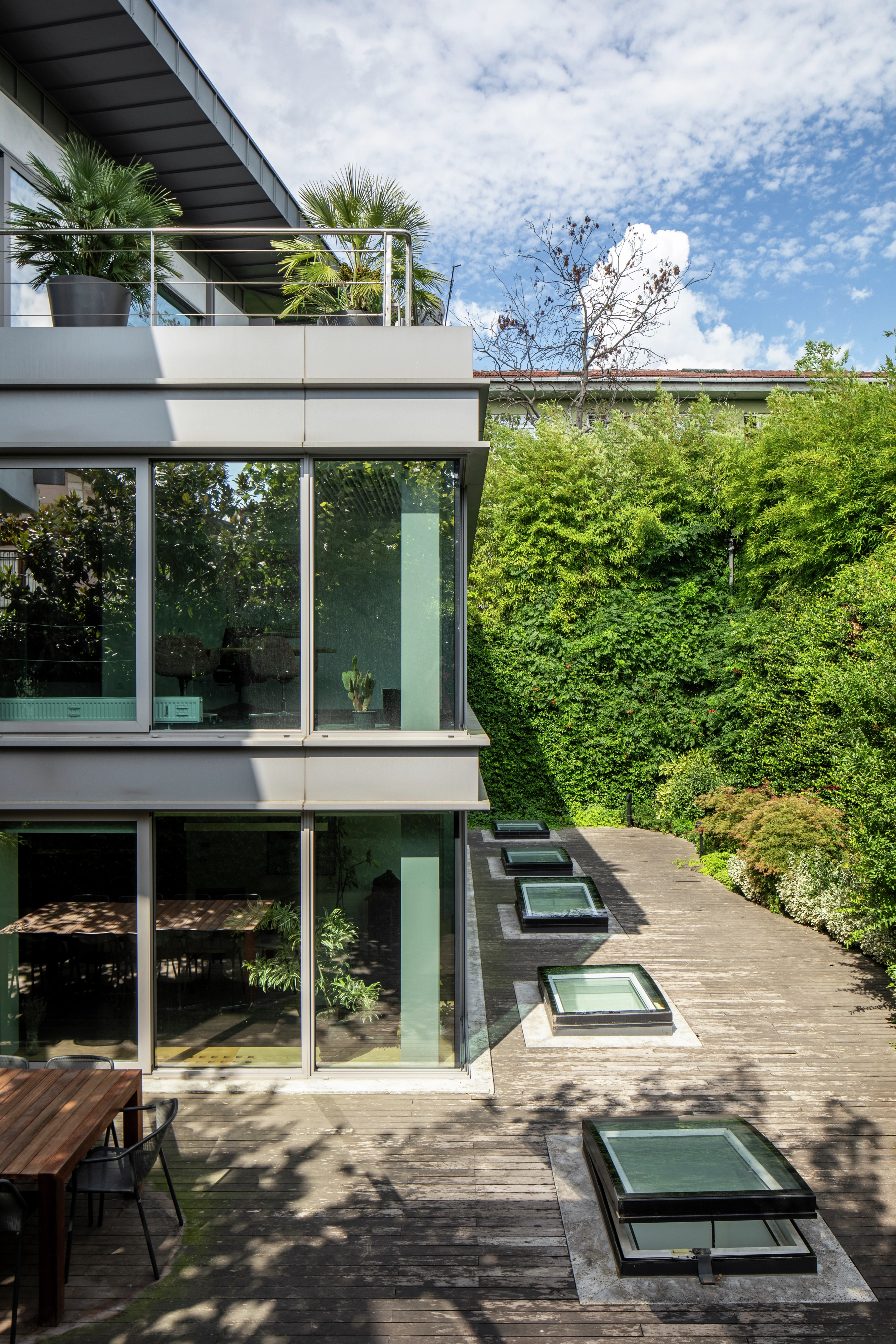Modern building with large windows and garden view, VELUX roof windows visible.