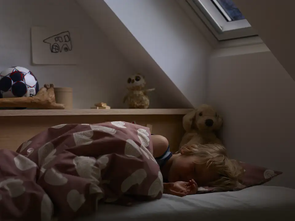 Enfant dormant dans un lit la nuit dans l'obscurité.