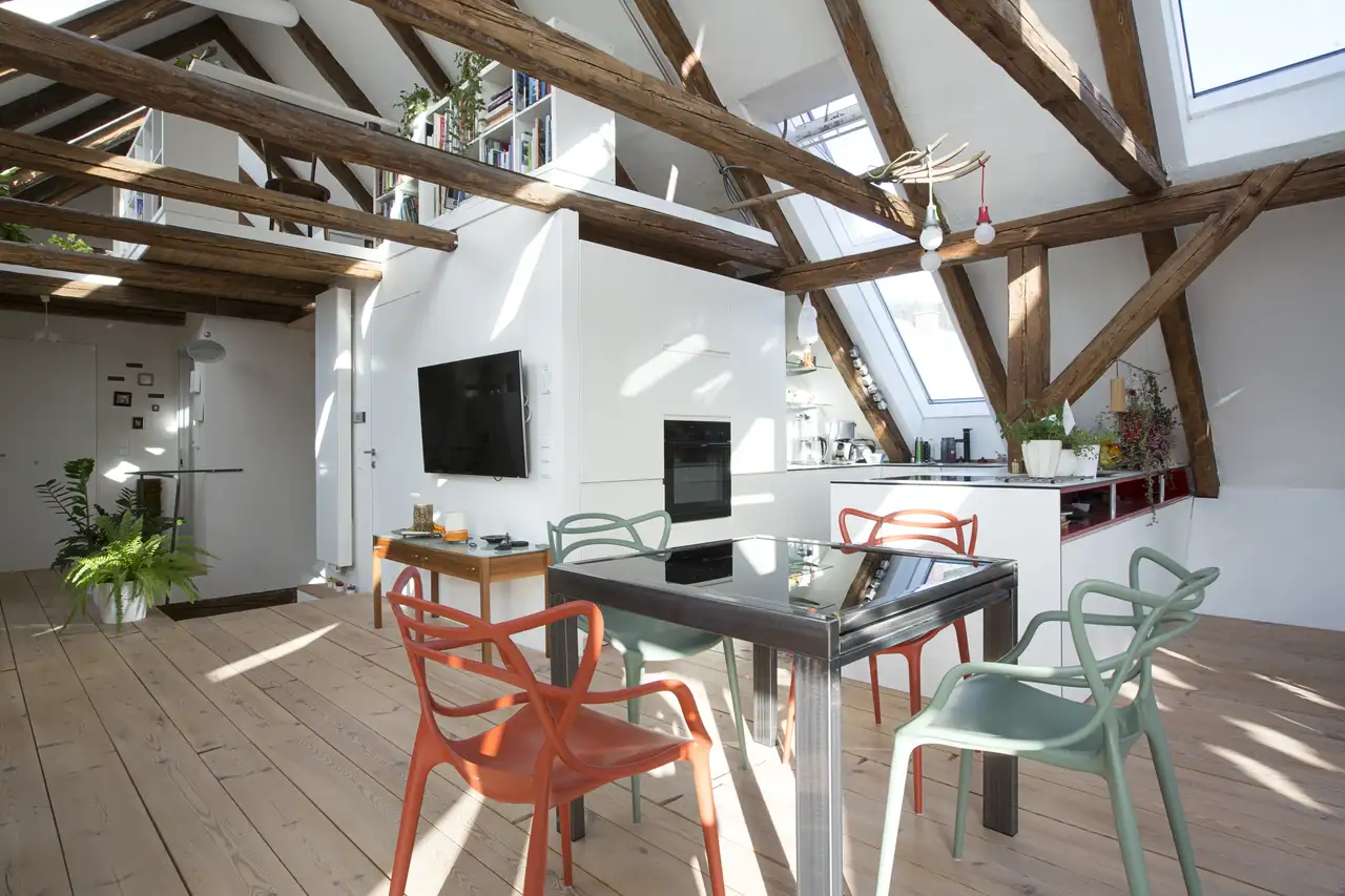 Open space con travi a vista, finestre per tetti VELUX e sedie colorate che donano vivacità e luce all’ambiente. 