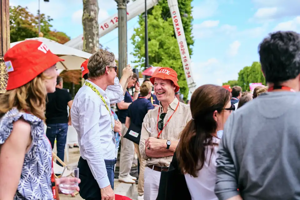 Množica na prostem dogodku, gledalci Tour de France z rdečimi klobuki.