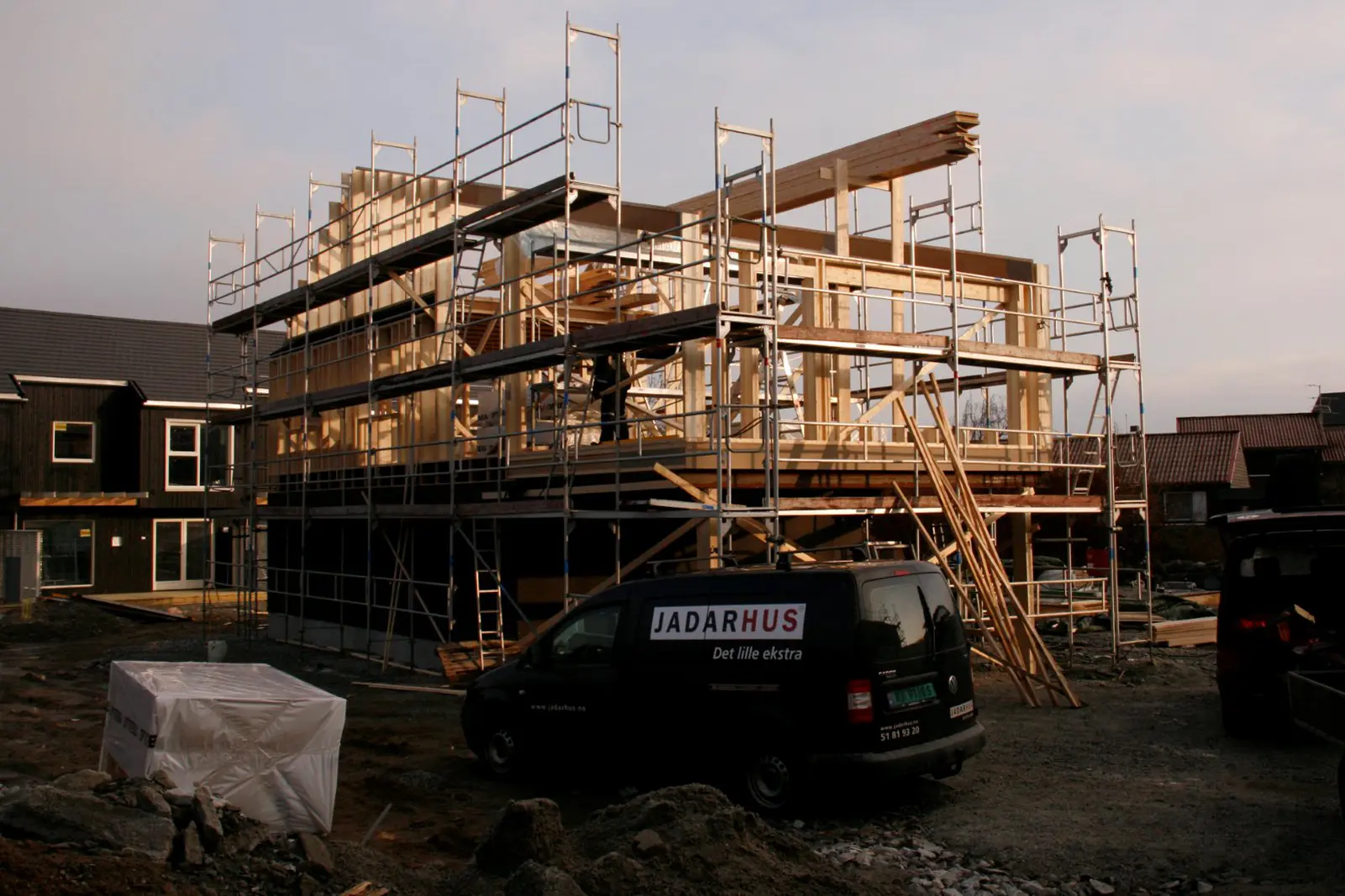 Clădire rezidențială în construcție cu schele și structură din lemn.