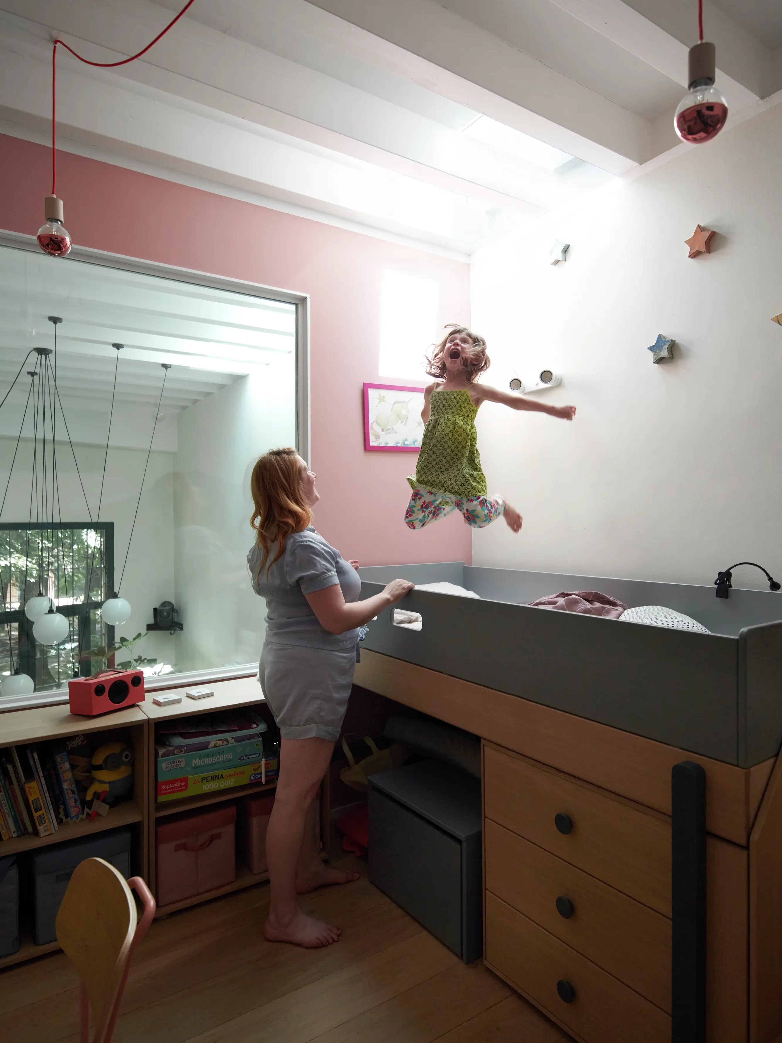 Bambino in una colorata stanza dei bambini con decorazioni a stelle sulla parete e una finestra per tetti VELUX.