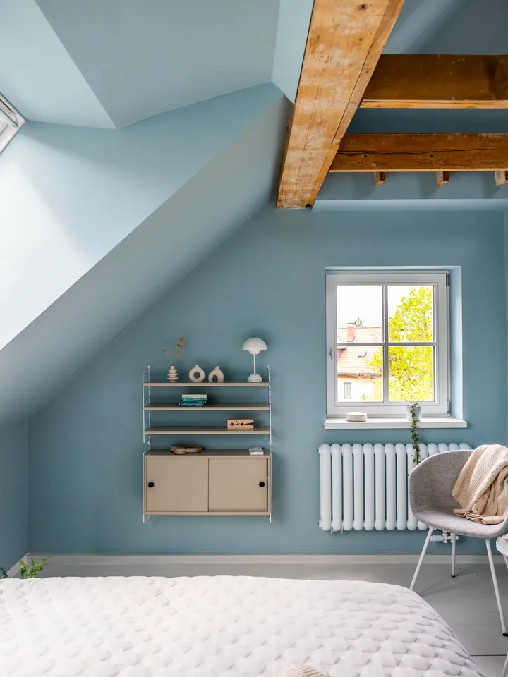 Minimalistična spalnica z modrimi stenami, polico in razkritim lesenim tramom.| VELUX 