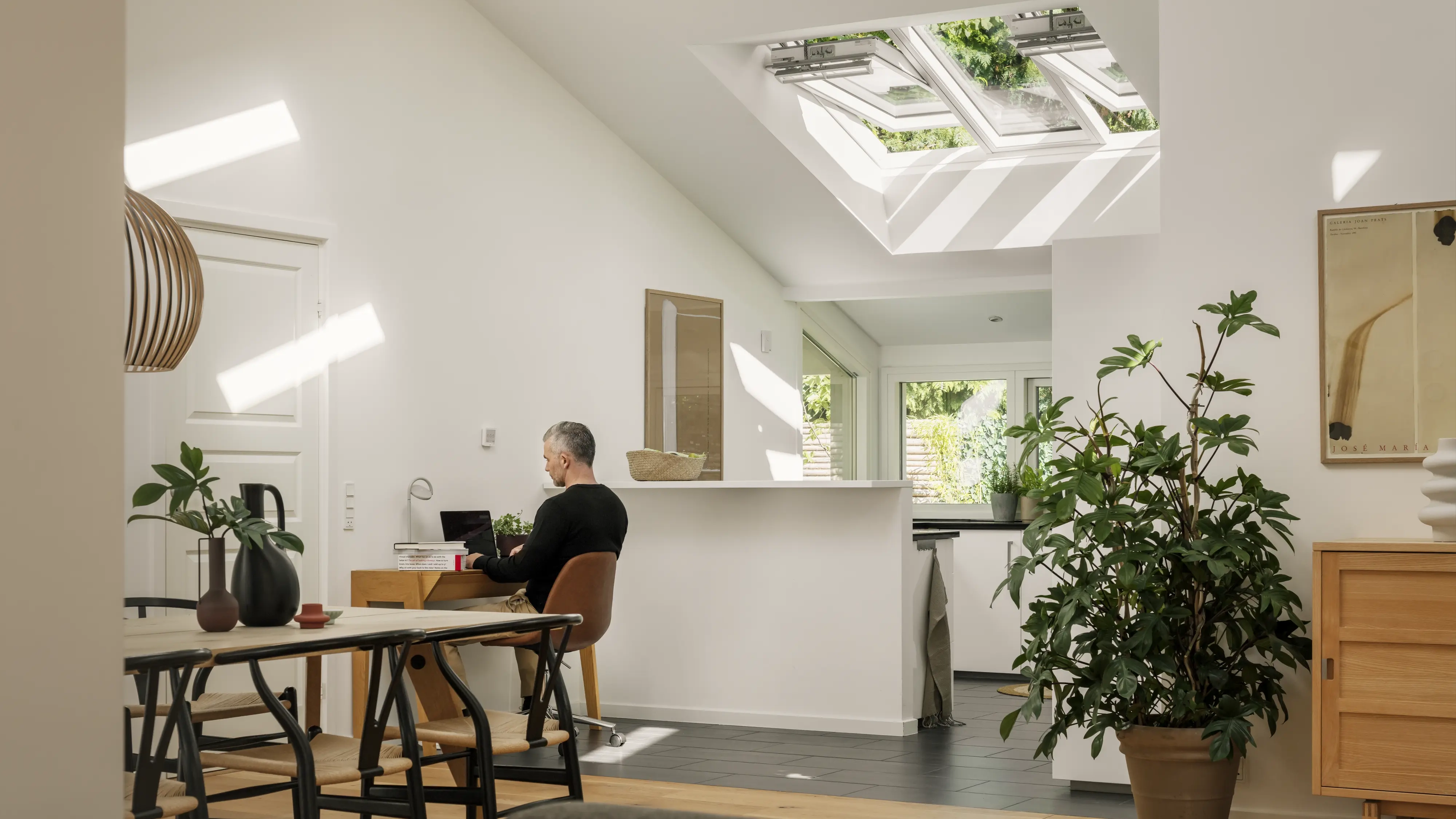 Soggiorno e cucina con angolo home office e finestre per tetti VELUX aperte sull’angolo cucina