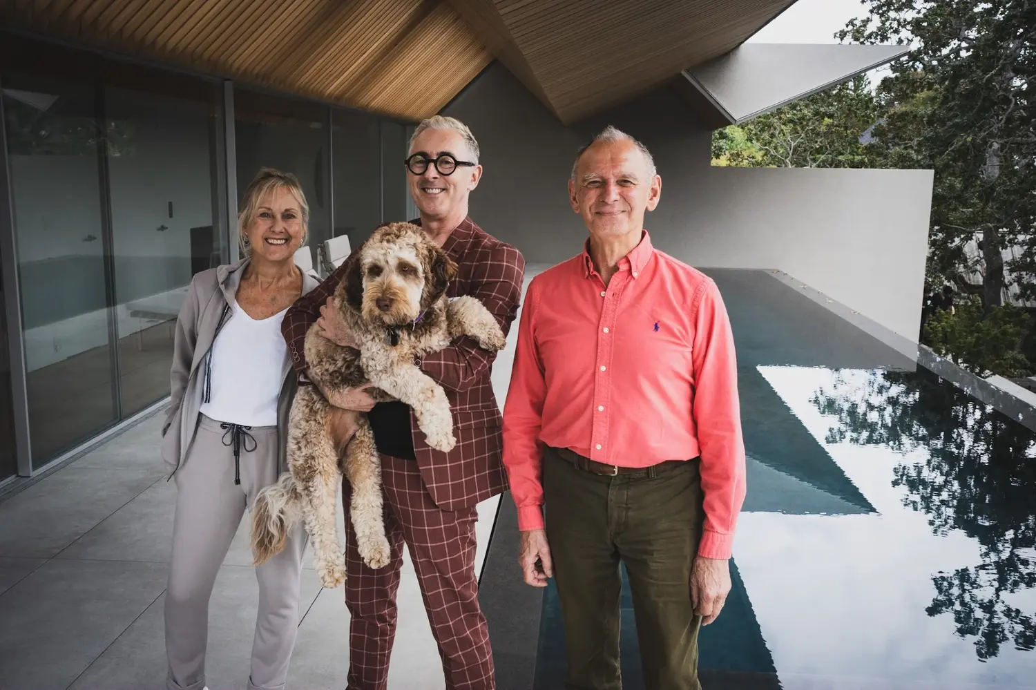 Alan Cumming holding dog with man and wife next to him