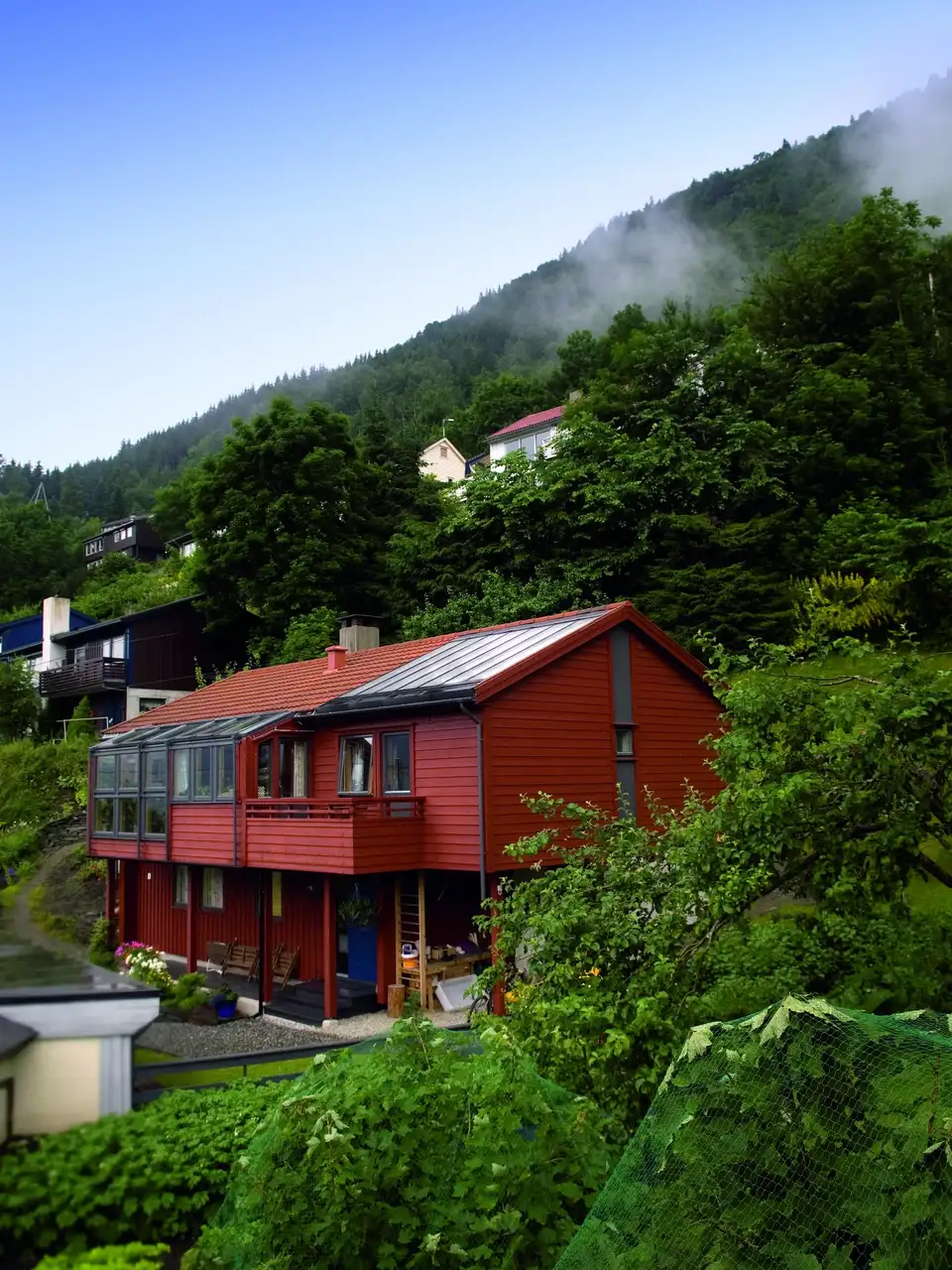 Casa rossa in montagna con tetto in lamiera, finestre per tetti VELUX e balcone.
