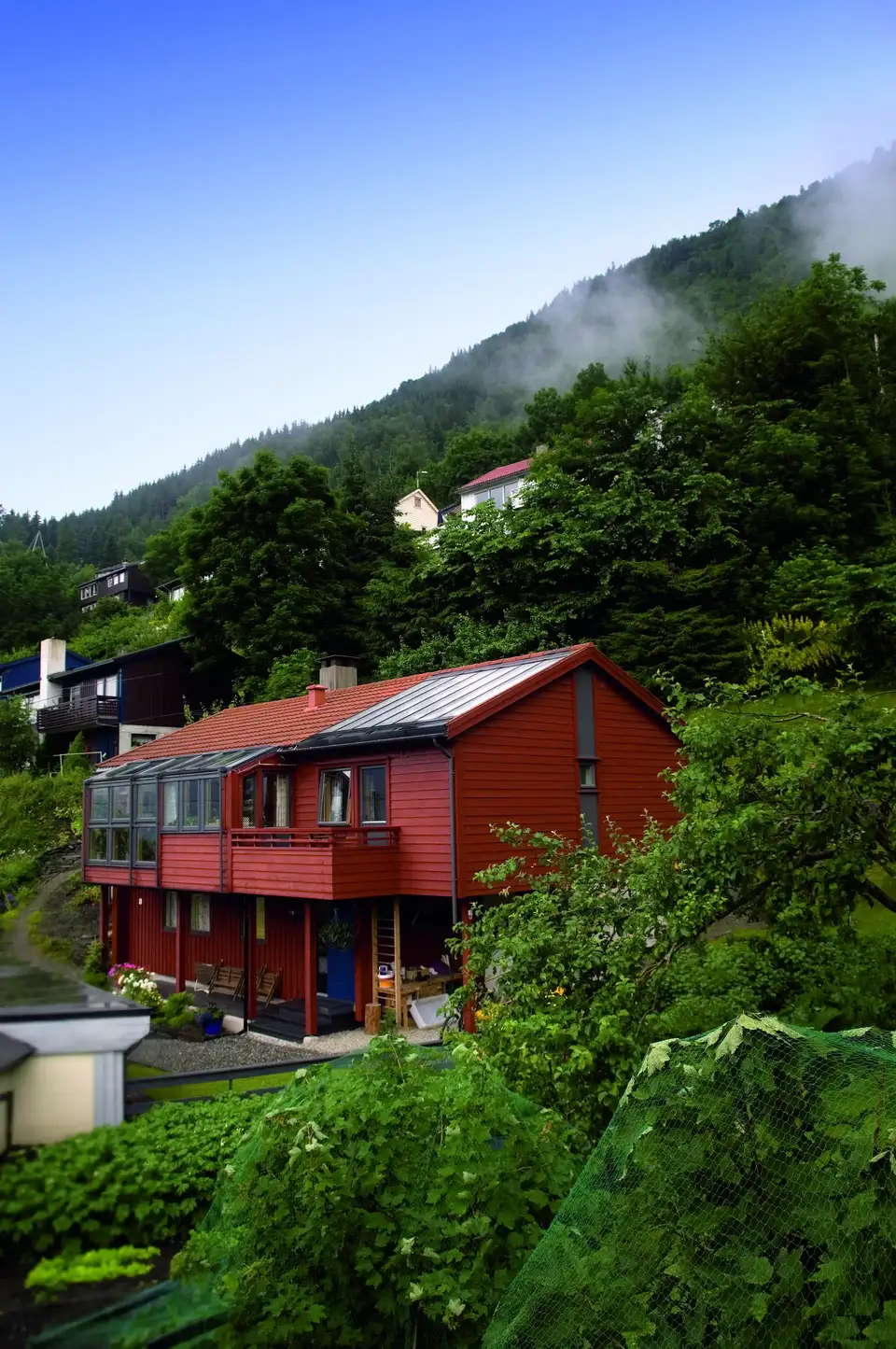 maison rouge en montagne avec toit en tôle, fenêtres de toit VELUX et balcon