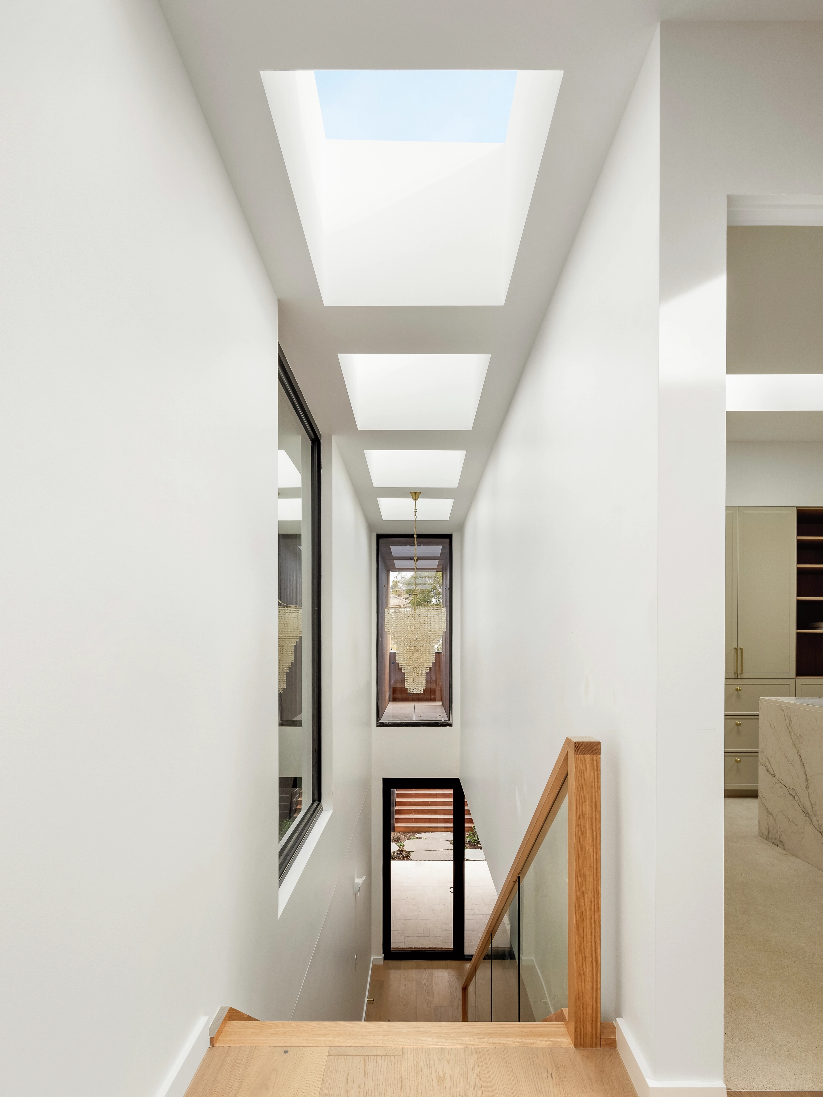 Modern stairwell lit by multiple VELUX flat roof windows in a bright white hallway.