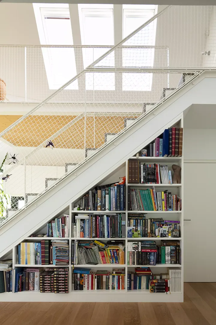Maßgefertigtes Bücherregal unter einem Stiegenhaus mit VELUX Dachflächenfenstern, die den Raum erhellen.