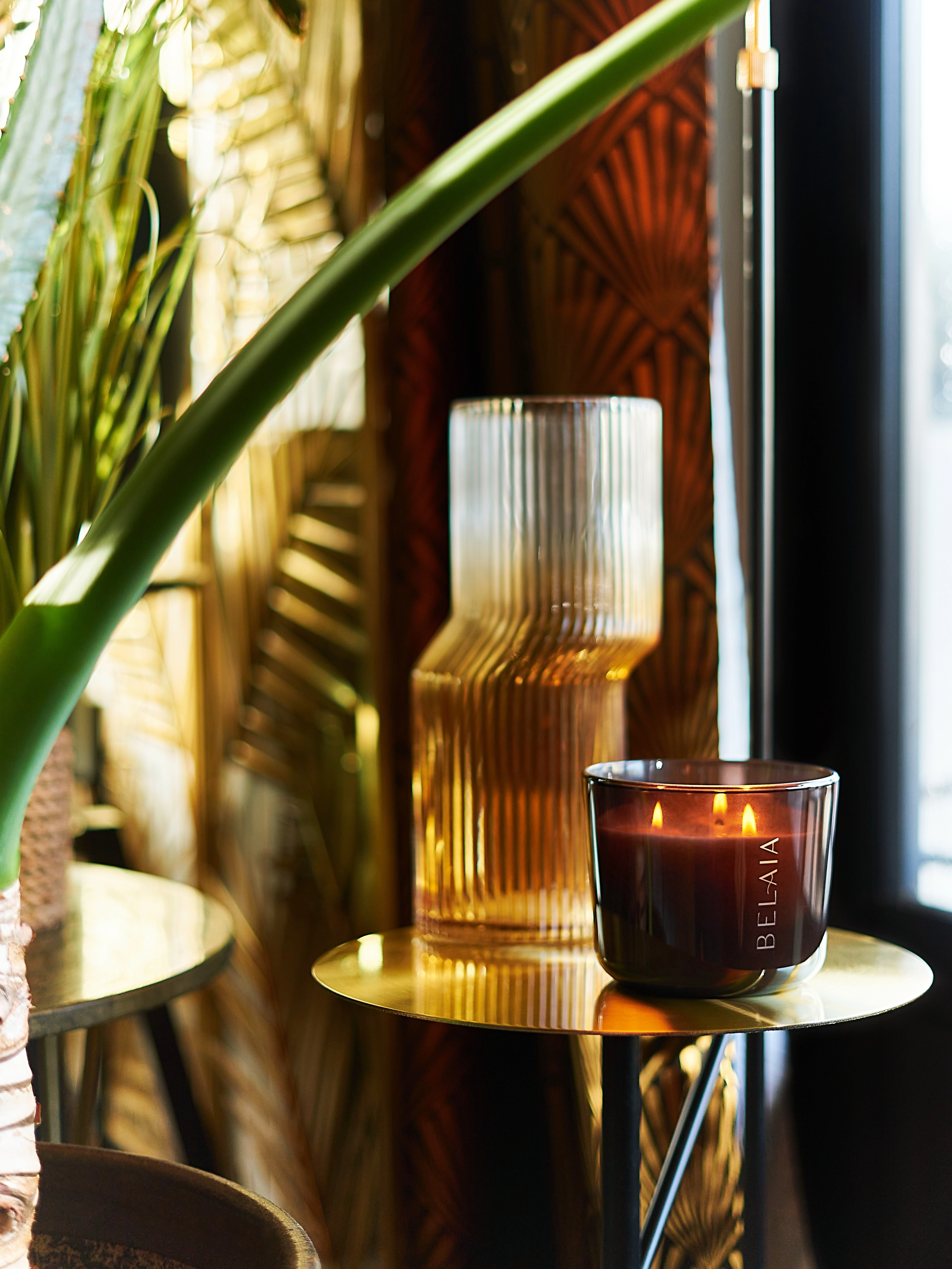 Goldener Beistelltisch mit brennender Duftkerze und gerippter Glasvase | VELUX Magazin 