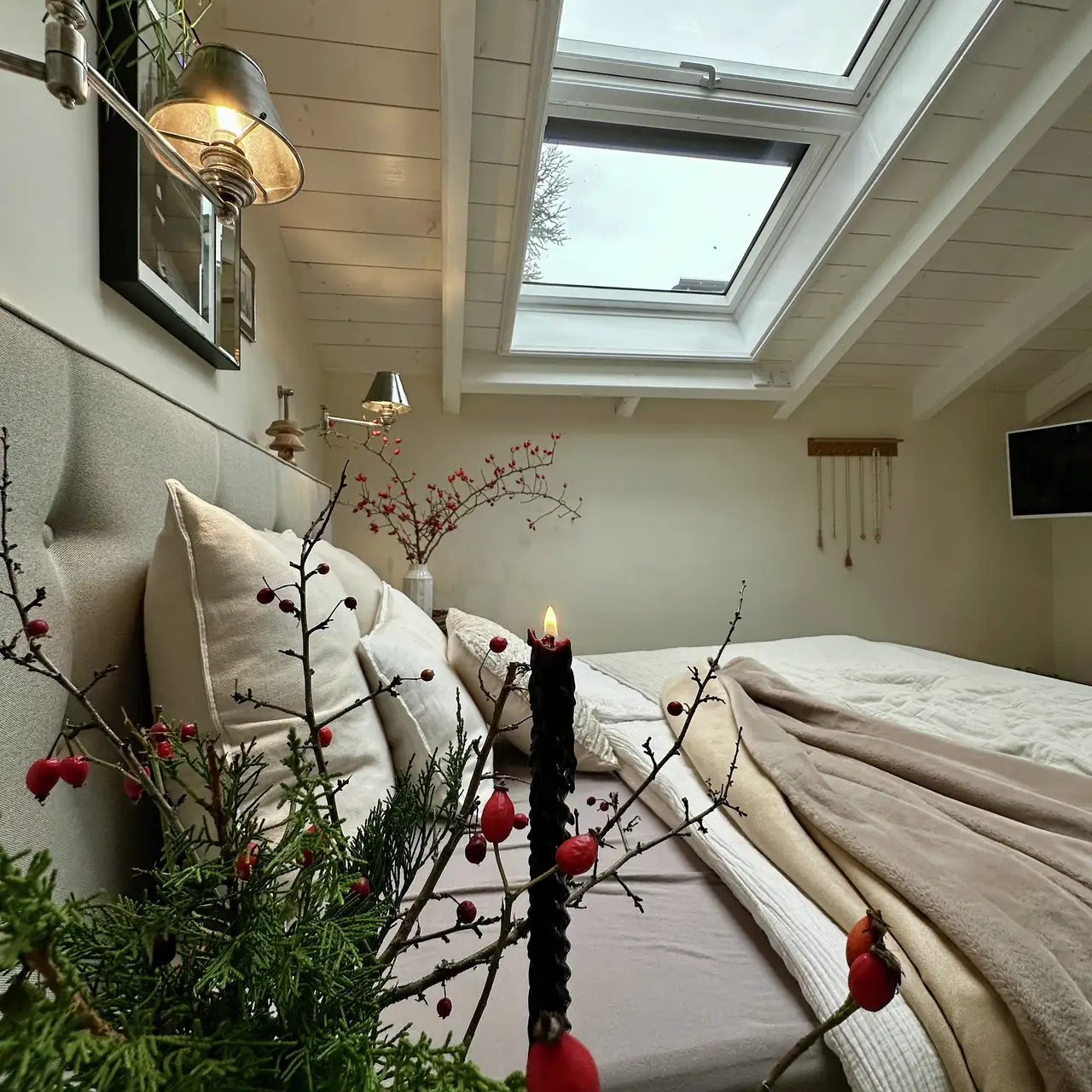 Camera da letto con tessuti morbidi e candele natalizie, illuminata dalla luce in entrata dalle finestre per tetti VELUX.