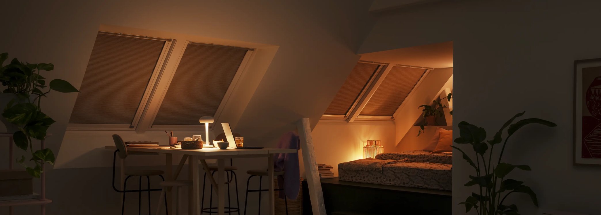 Attic room with sloped ceiling, VELUX roof windows with blinds, dining and bed area.