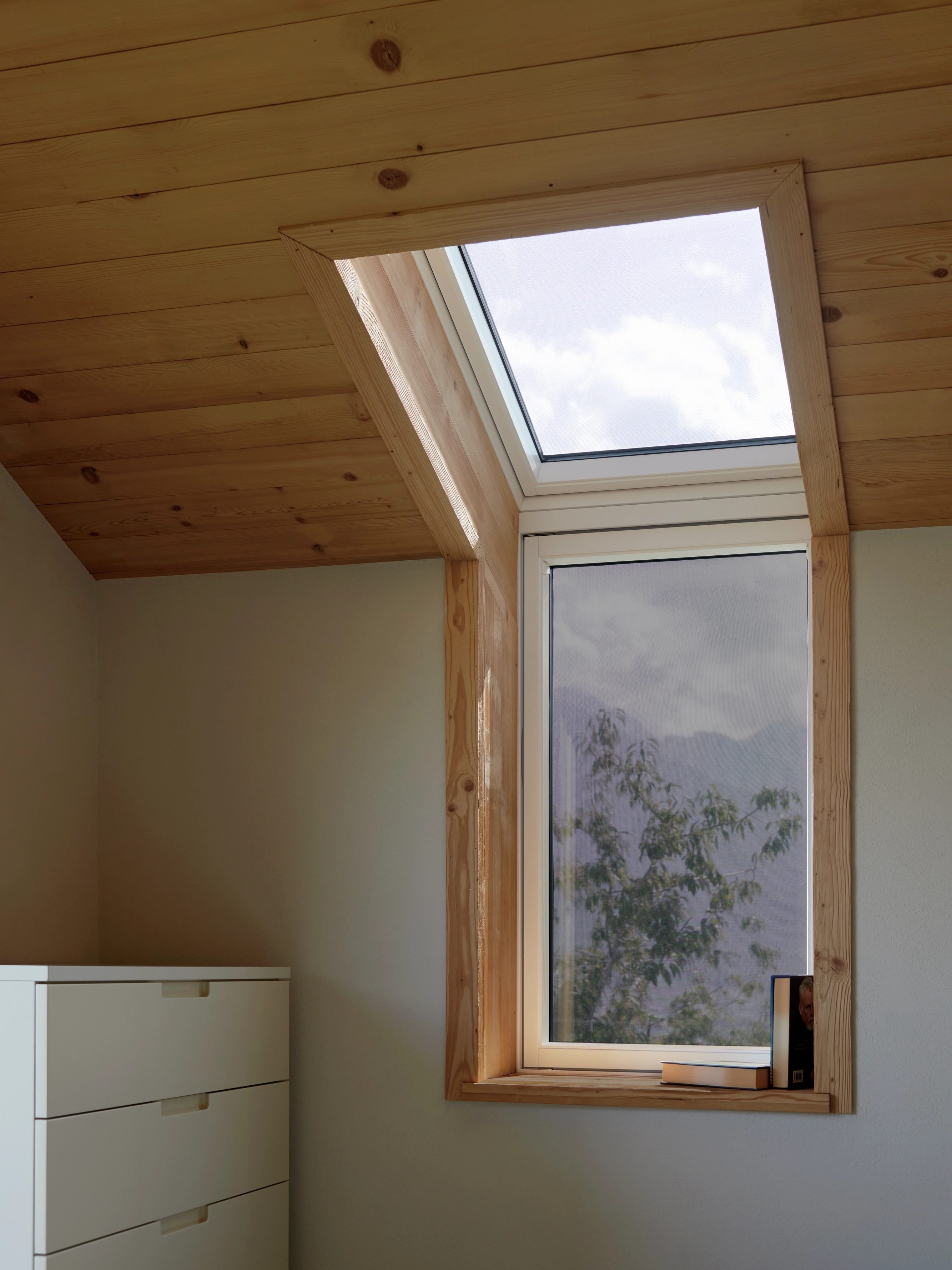 Camera mansardata con soffitto inclinato e finestra per tetti VELUX, illuminata dalla luce naturale.