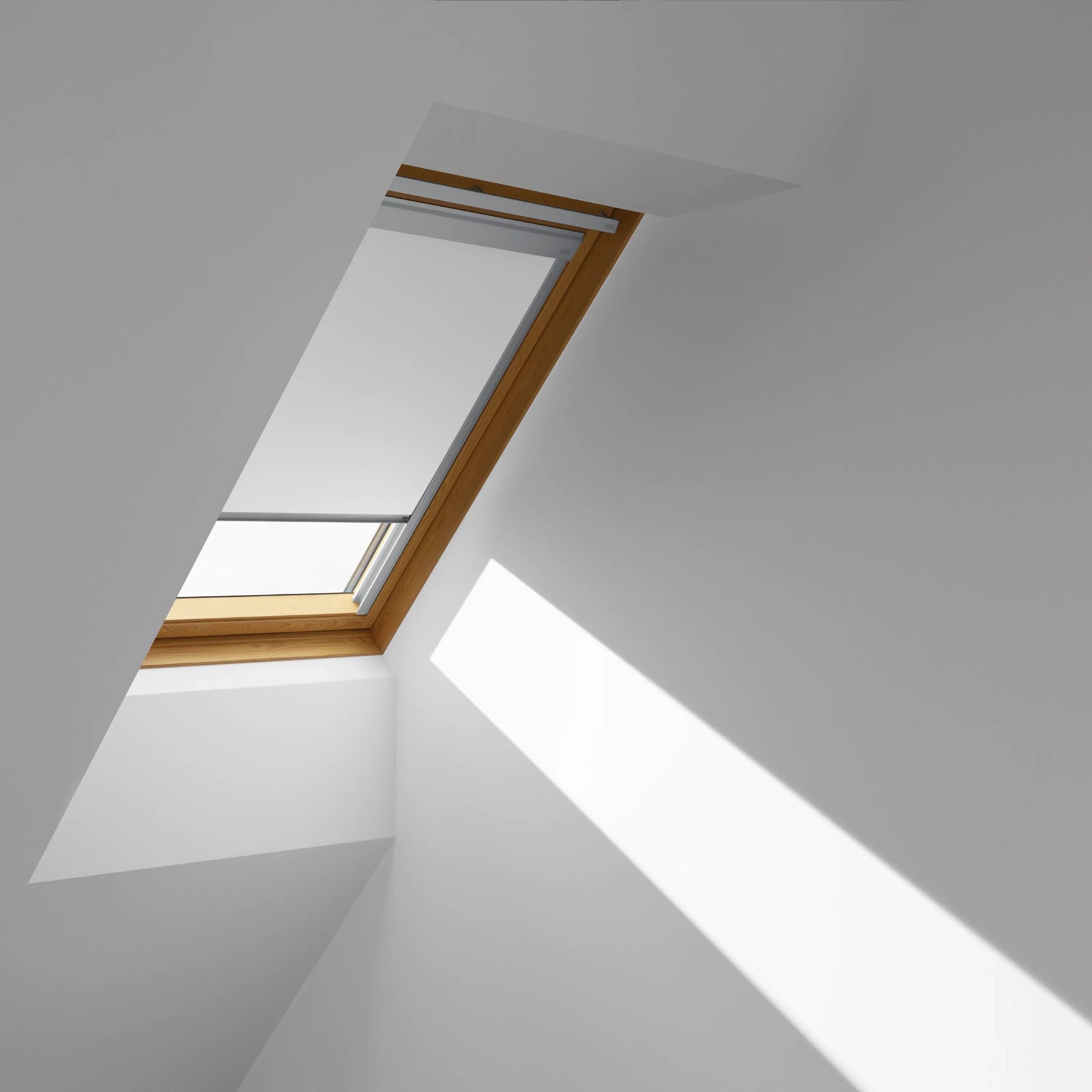 Attic with sloped ceiling and VELUX roof window, natural light streaming in.