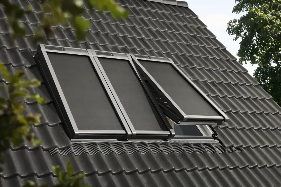 Hellend dak met drie VELUX dakramen, elk voorzien van buitenzonwering. 