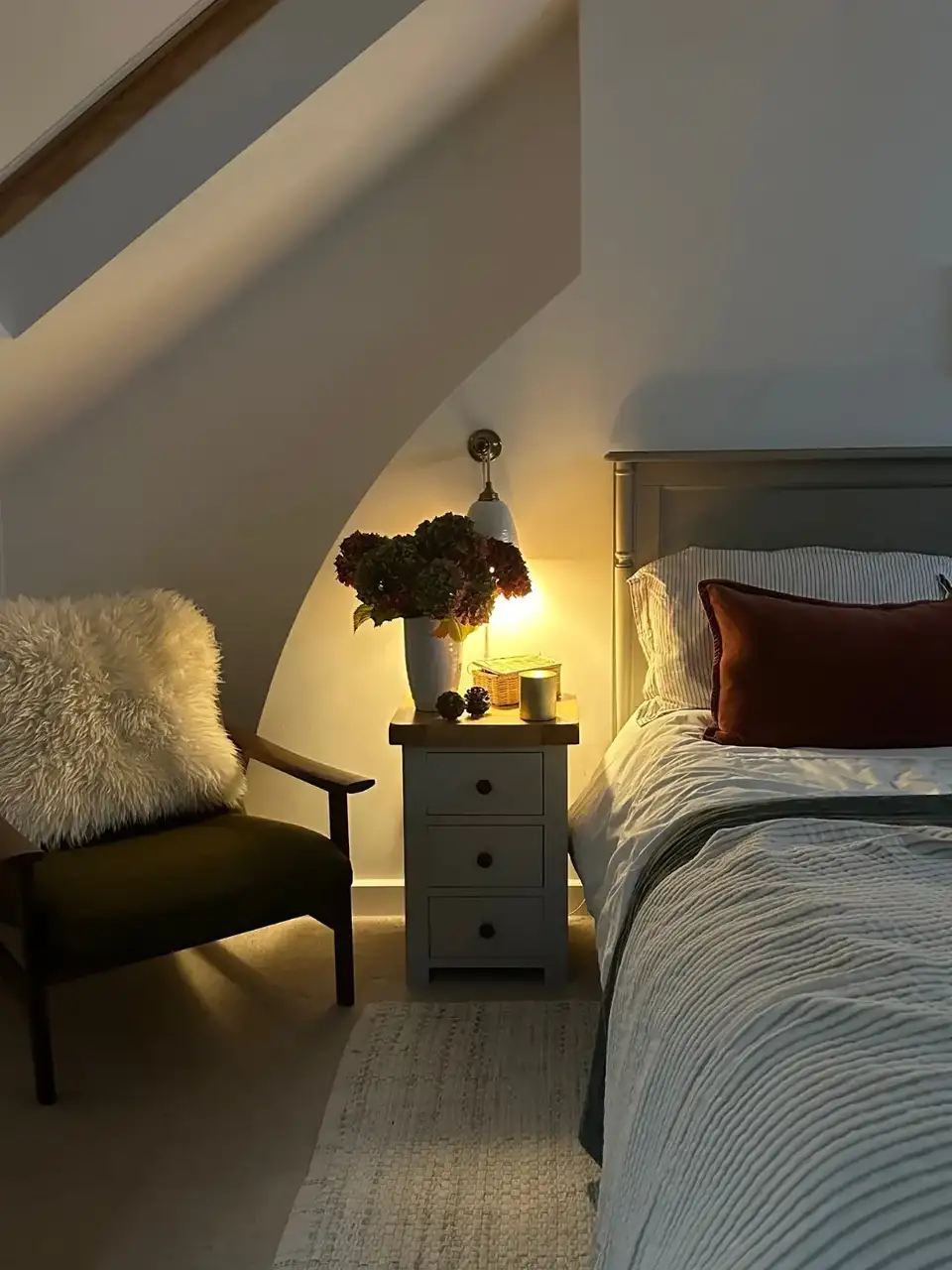 Attic bedroom with sloped ceiling, VELUX roof window, and cozy decor.
